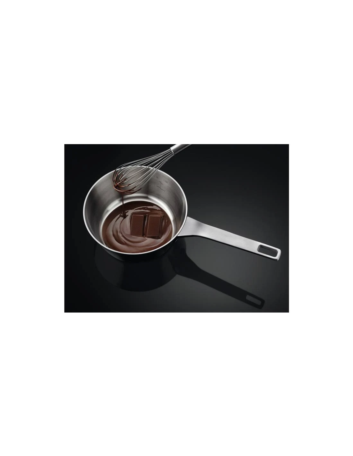 Un pentolino in acciaio inox con cioccolato e una frusta su una superficie nera.