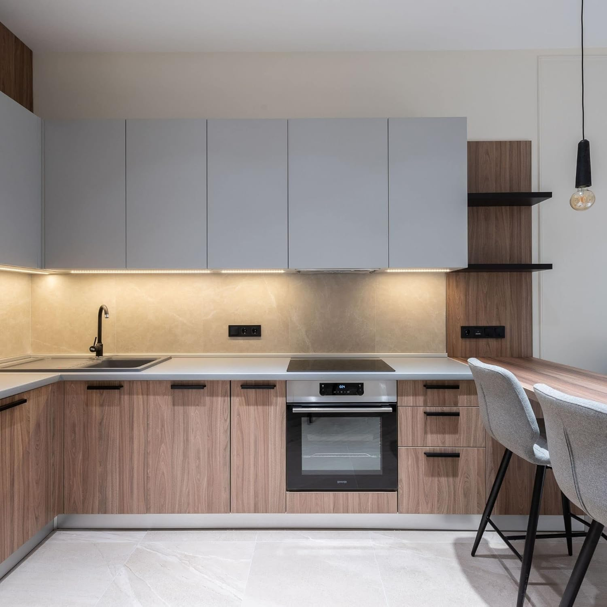 Cucina moderna con armadi, forno e due sgabelli da bar.