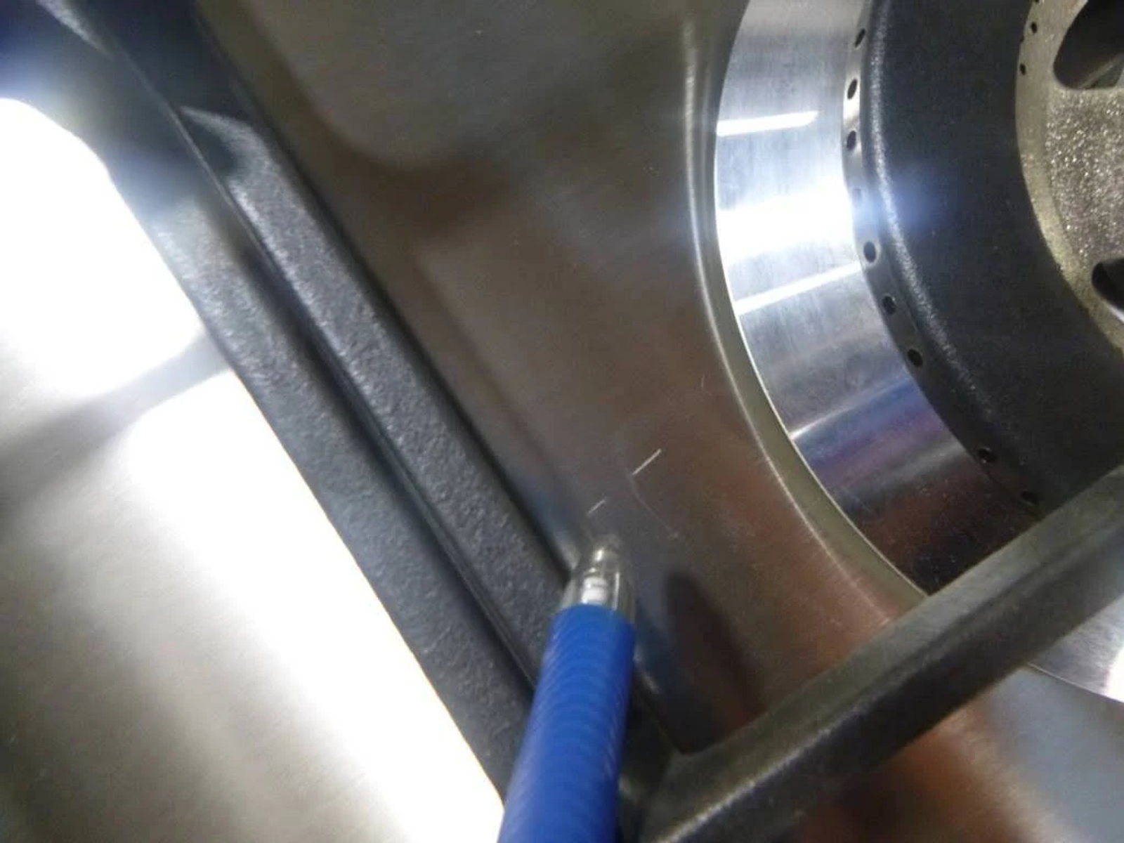 Primer plano de un componente de acero con un bolígrafo azul. El bolígrafo está cerca de la superficie.