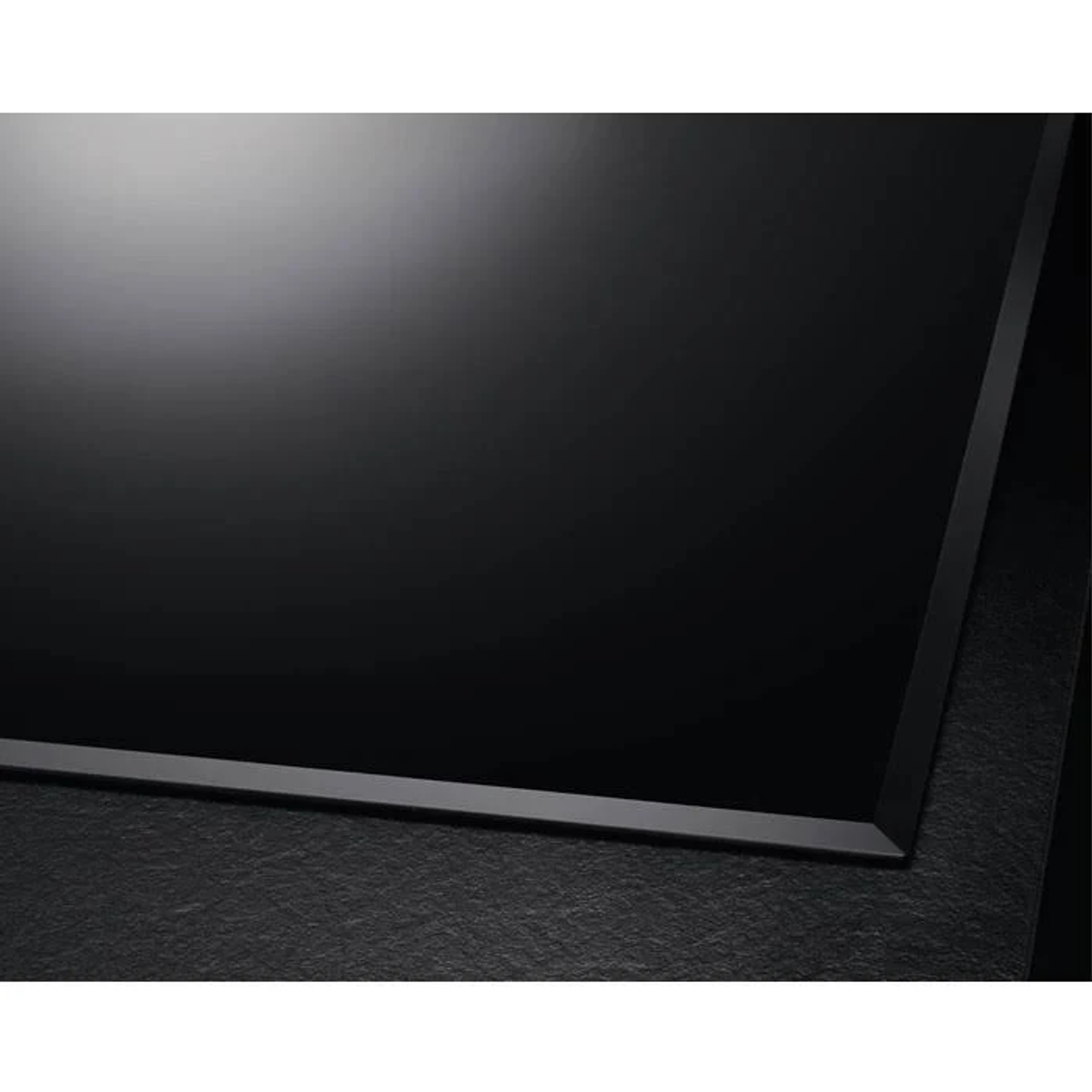 Primo piano della superficie di un elegante piano cottura a induzione nero, con un design minimalista.