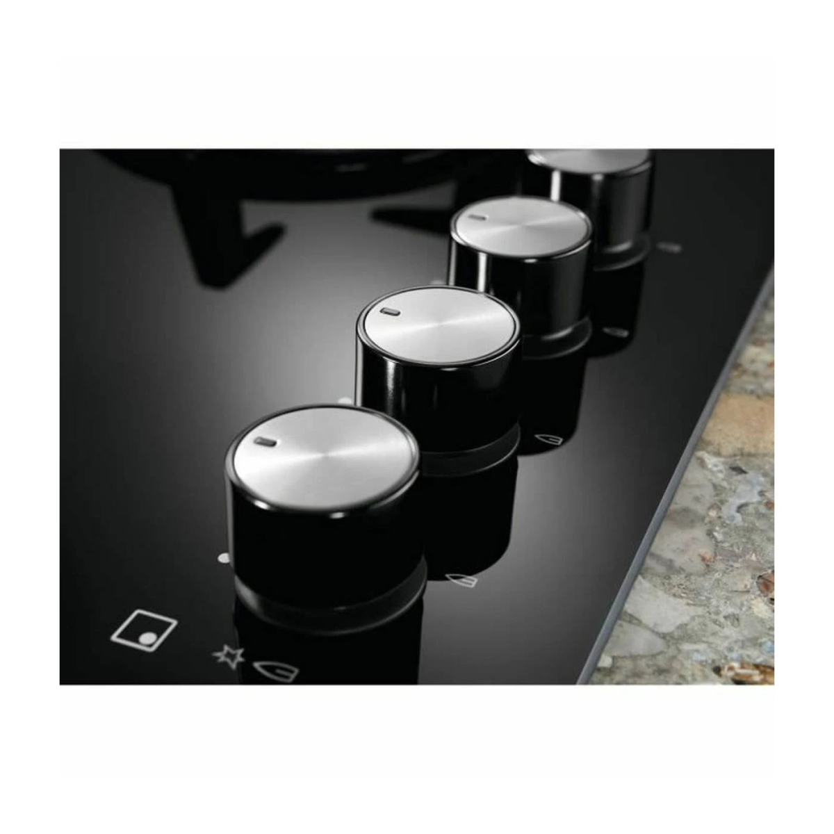 Zbliżenie na czarną płytę grzejną z czterema pokrętłami.