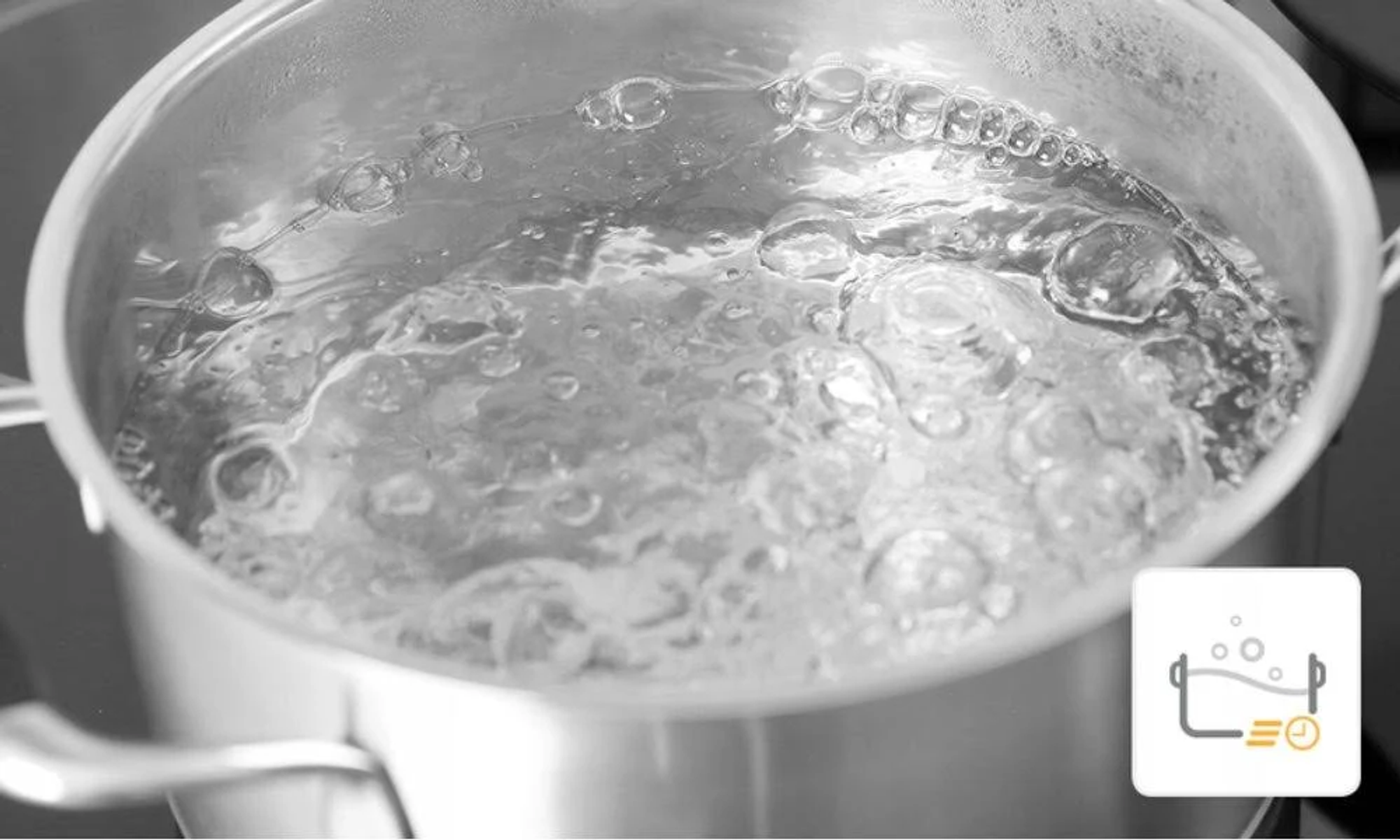 Garnek ze stali nierdzewnej z wrzącą wodą i bąbelkami na płycie kuchennej.