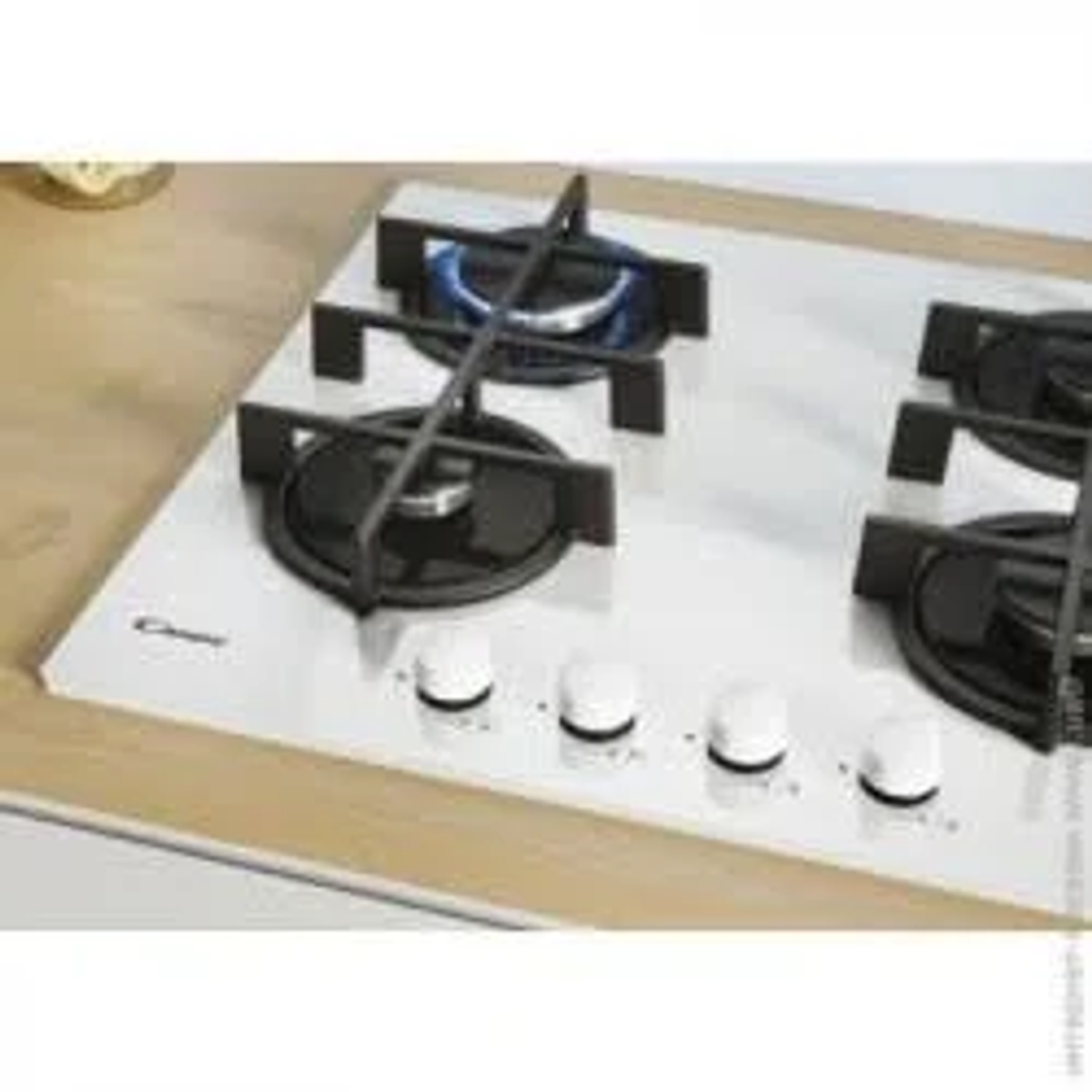 Płyta gazowa z czterema palnikami, biała powierzchnia, białe pokrętła. Marka Candy.