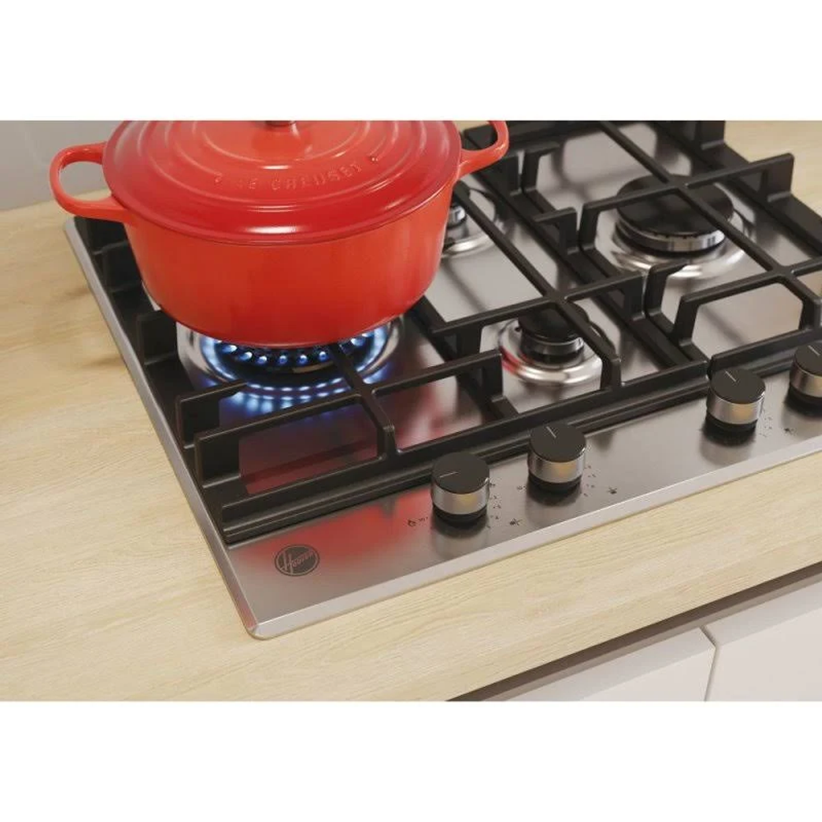 Piano cottura con pentola rossa, fiamme blu, quattro fuochi, piano di lavoro in legno chiaro. Marchio Hoover.