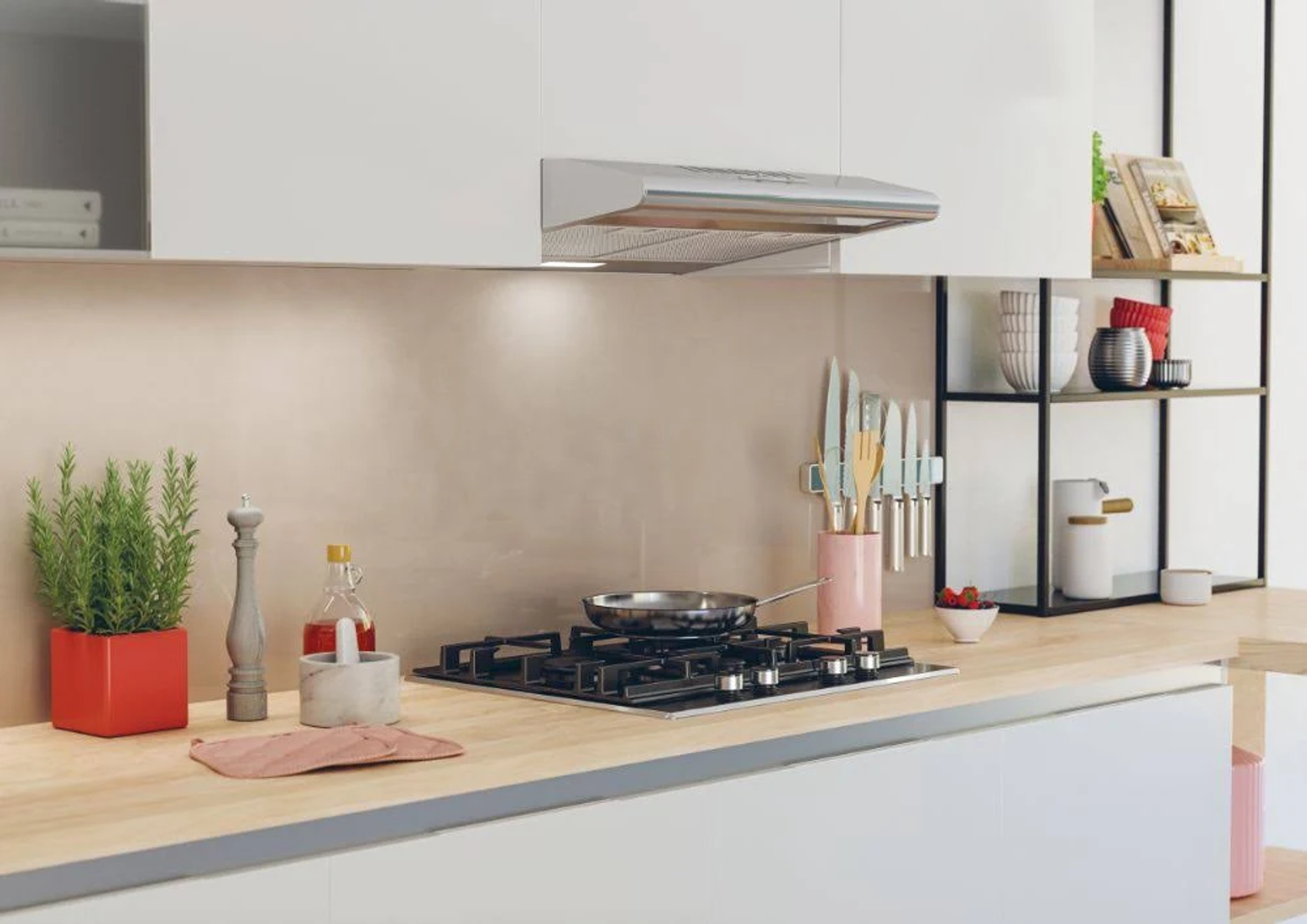 Scena di cucina con piano cottura, piante e accessori su un piano di lavoro in legno.