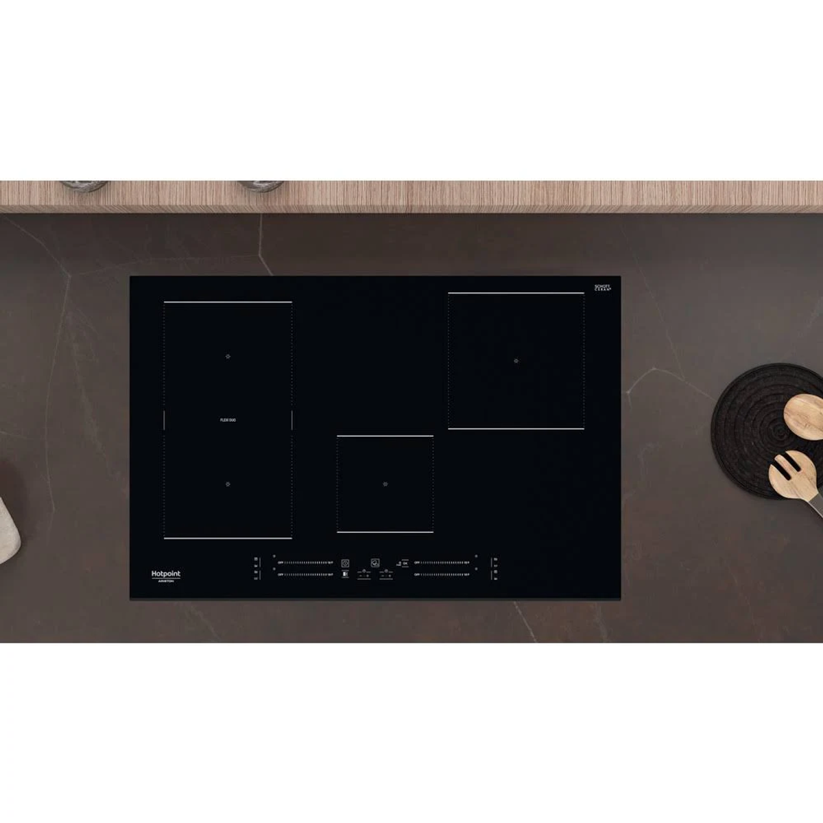 Placa de inducción negra con tres zonas de cocción y controles táctiles. Una cuchara de madera a la derecha.