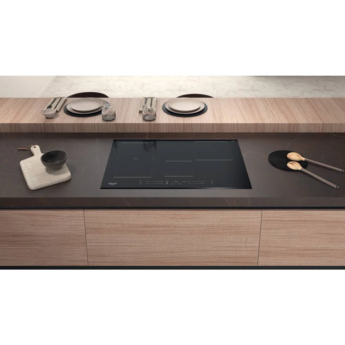 Cocina moderna con encimera negra. Armarios de madera debajo, utensilios cerca de la placa.