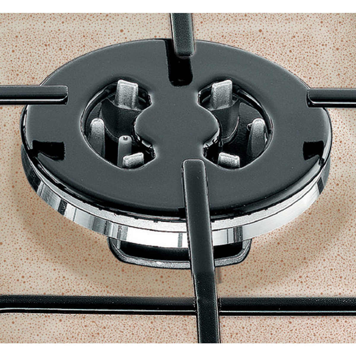 Zbliżenie palnika płyty grzewczej. Czarny palnik z metalowym pierścieniem na nakrapianej beżowej powierzchni.