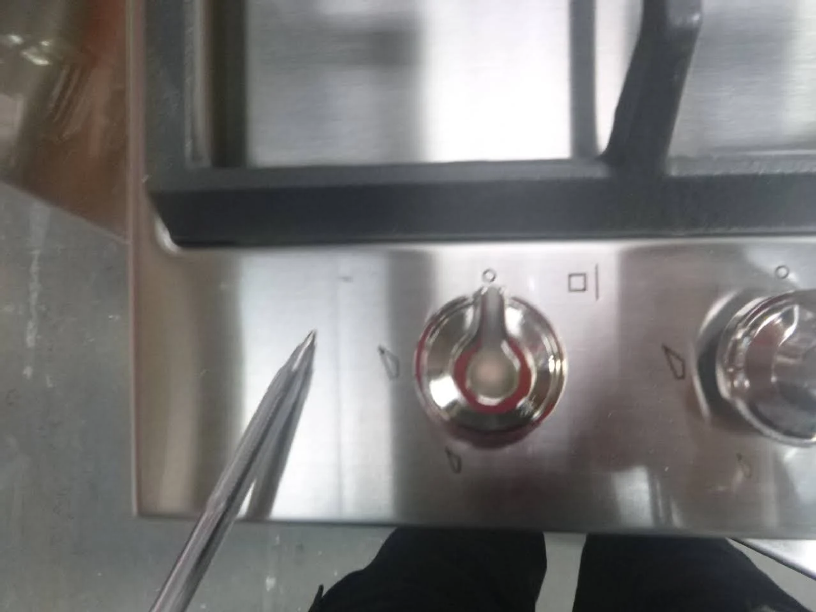 Primer plano de una placa de gas de acero inoxidable con un destornillador.