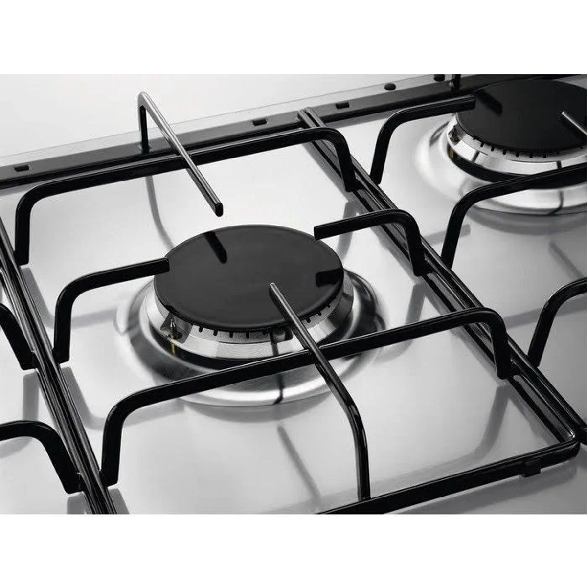 Primer plano de una encimera de gas de acero inoxidable. Se ven tapas y rejillas negras que reflejan la luz.