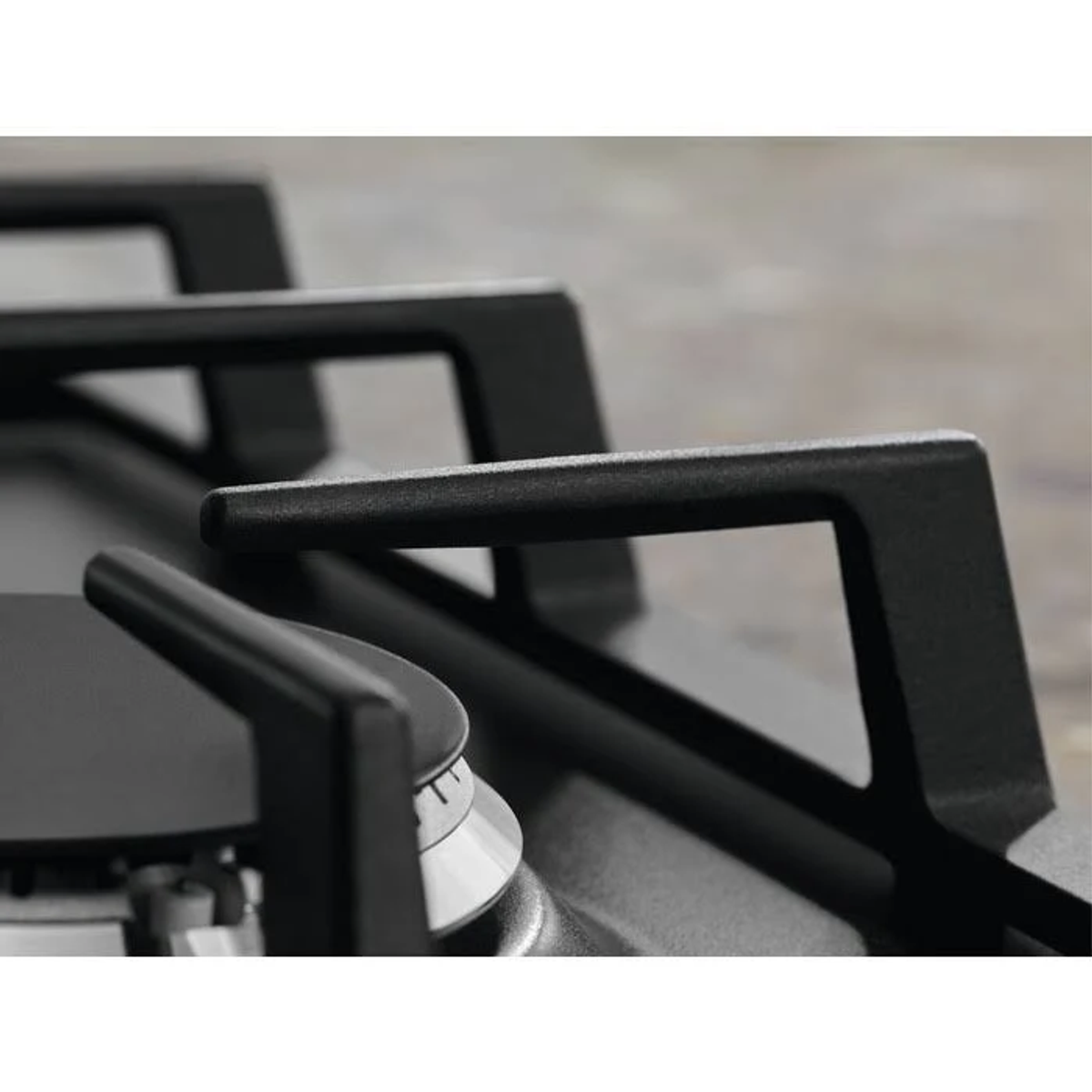 Primer plano de un soporte de quemador de gas de metal negro sobre una placa vitrocerámica negra.