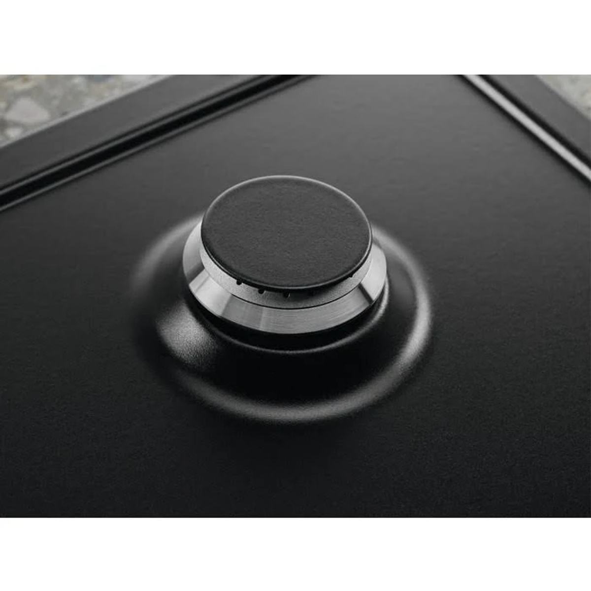 Primer plano de un quemador negro de encimera con un anillo plateado. Superficie brillante y reflectante.
