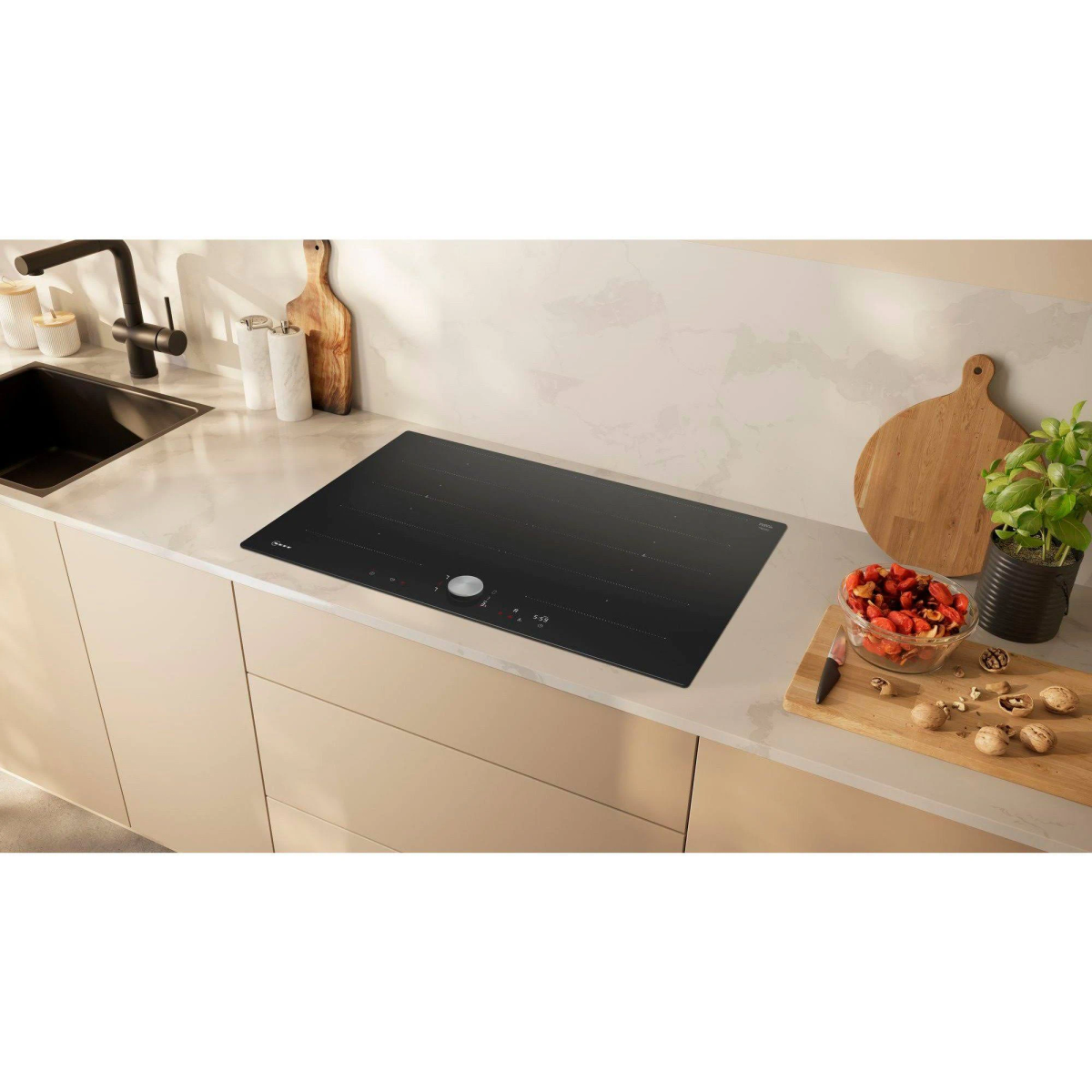 Piano cottura a induzione nero moderno su un piano di lavoro chiaro con utensili da cucina.