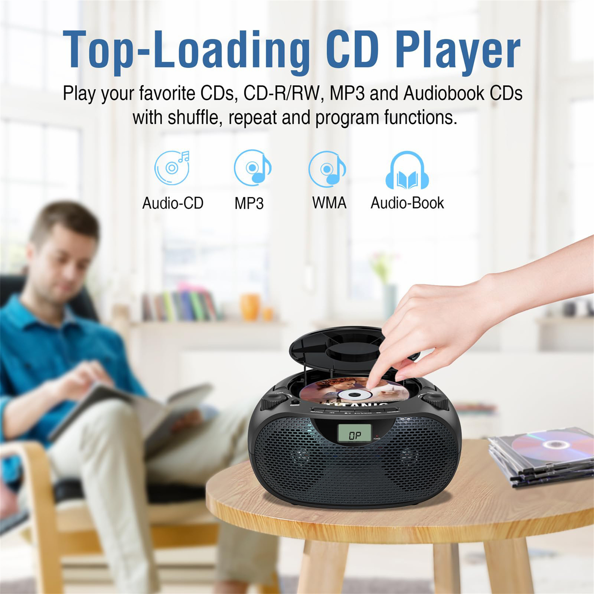 Ein Top-Loading-CD-Player mit einem Mann im Hintergrund. Der CD-Player steht auf einem Tisch mit CDs.