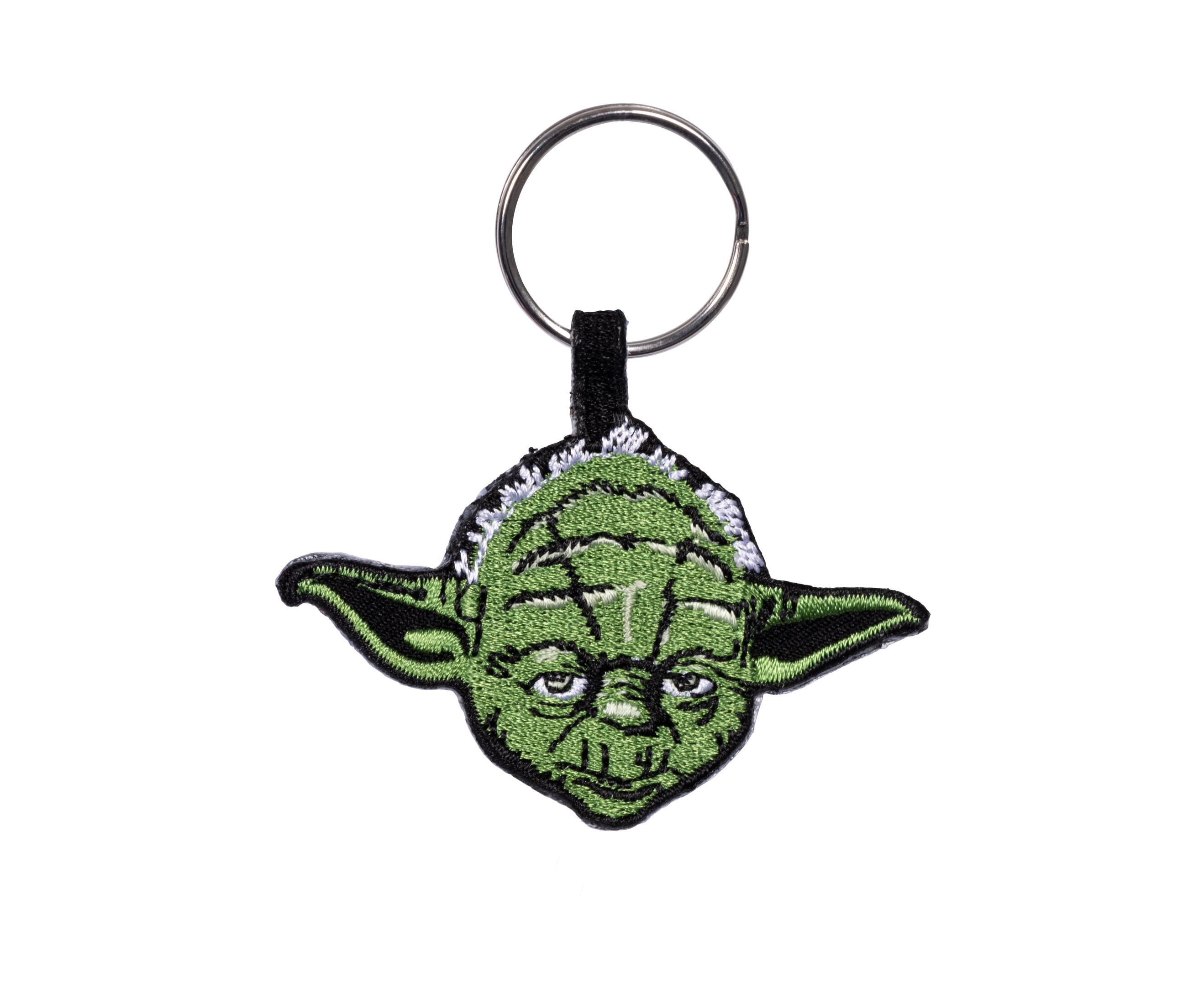 Yoda-Schlüsselanhänger auf Weiß. Grünes Gesicht, schwarzer Riemen, silberner Ring.