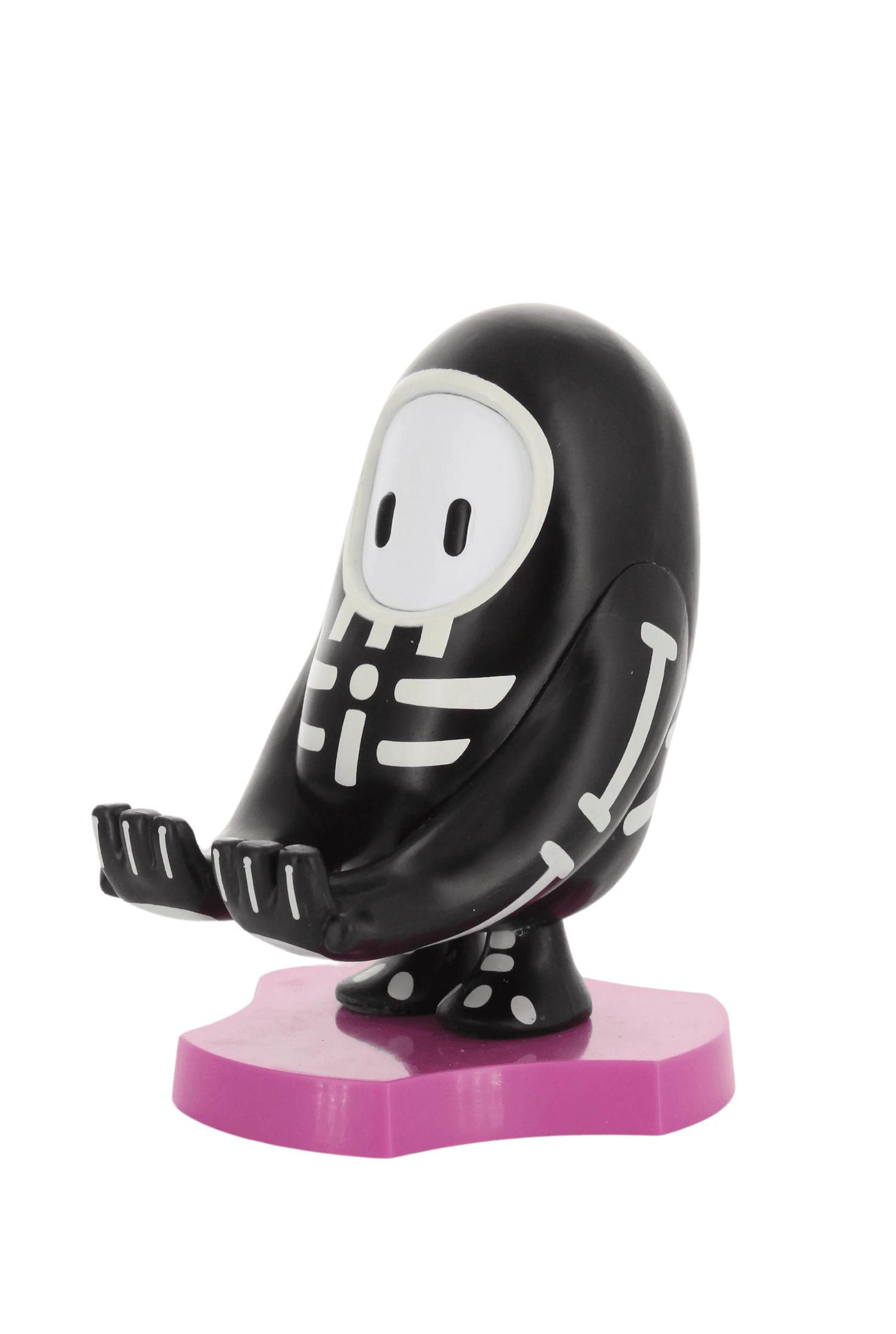 Una statuetta di scheletro di Fall Guys è su una base rosa. Ha un corpo nero e dettagli bianchi.