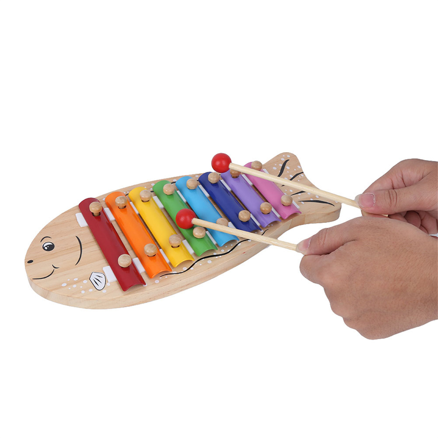 Ein hölzernes Xylophon in Fischform. Hände spielen es mit zwei Schlägeln.