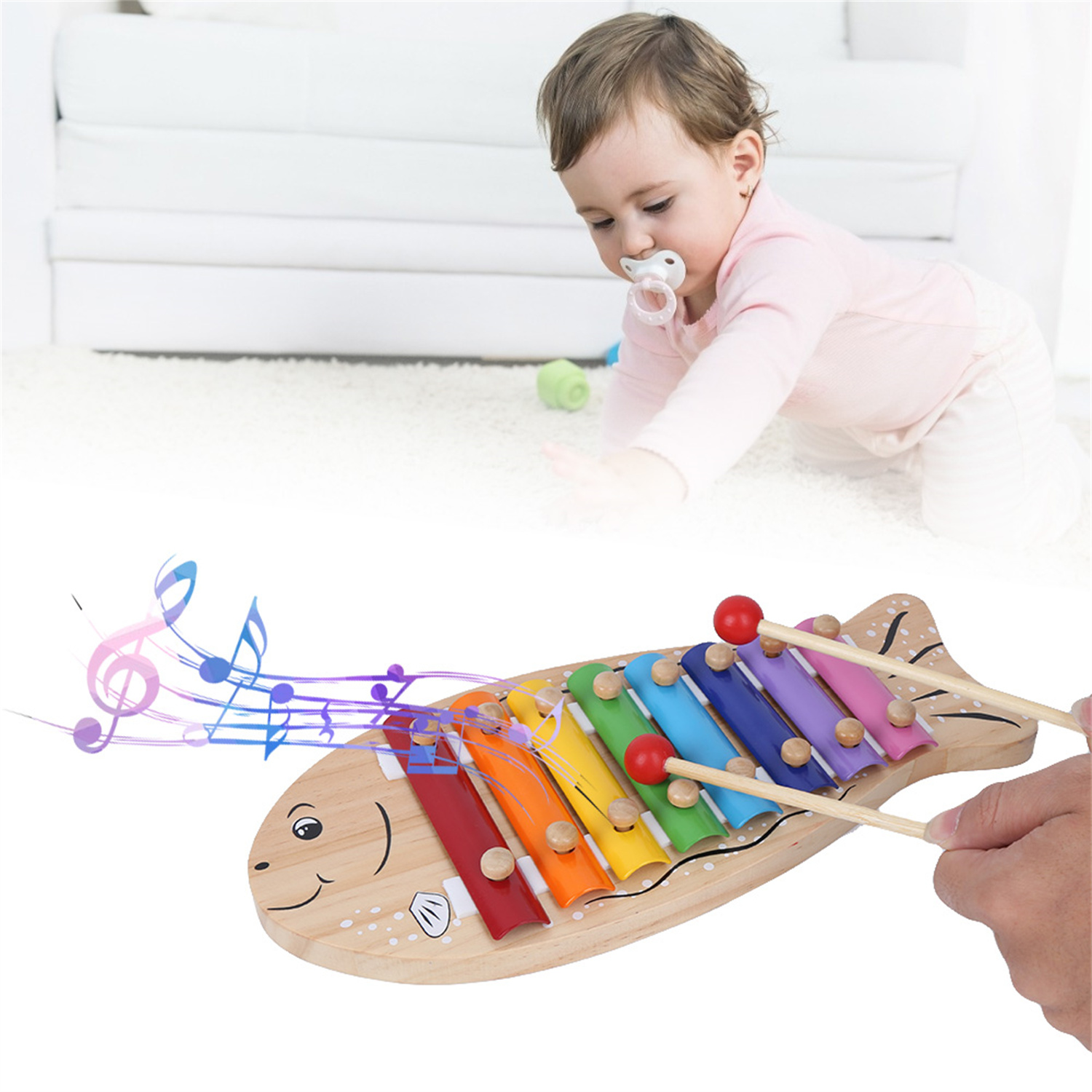Ein Baby greift nach einem hölzernen Xylophon-Spielzeug mit bunten Tasten und einem lächelnden Gesicht.