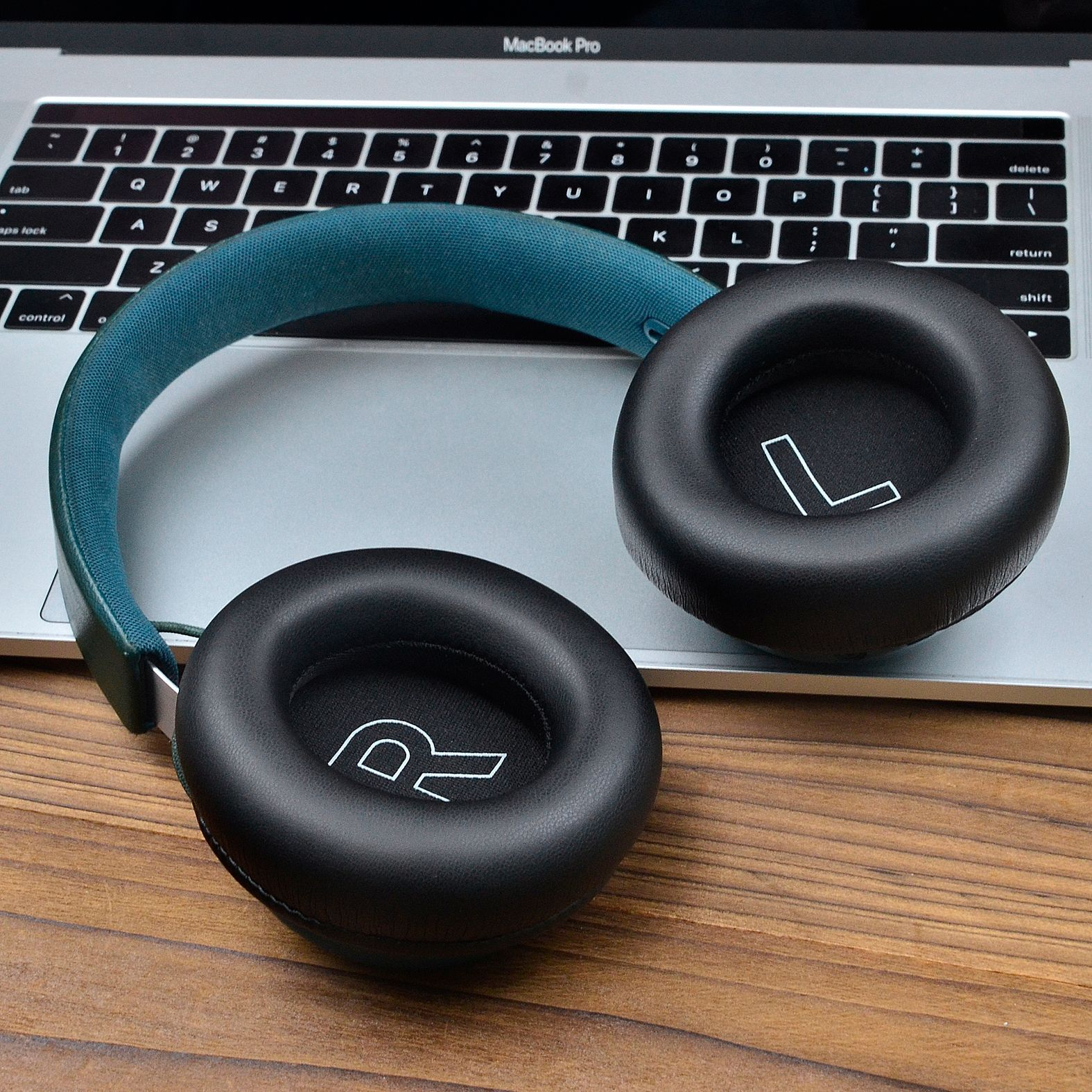 Słuchawki z oznaczeniami 'R' i 'L' na nausznikach, leżące na laptopie.