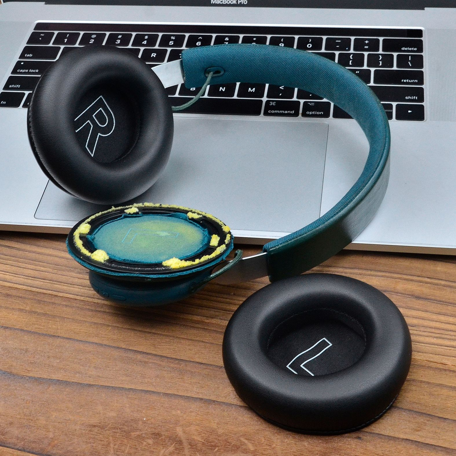 Słuchawki z czarnymi nausznicami i niebieskim pałąkiem na laptopie.