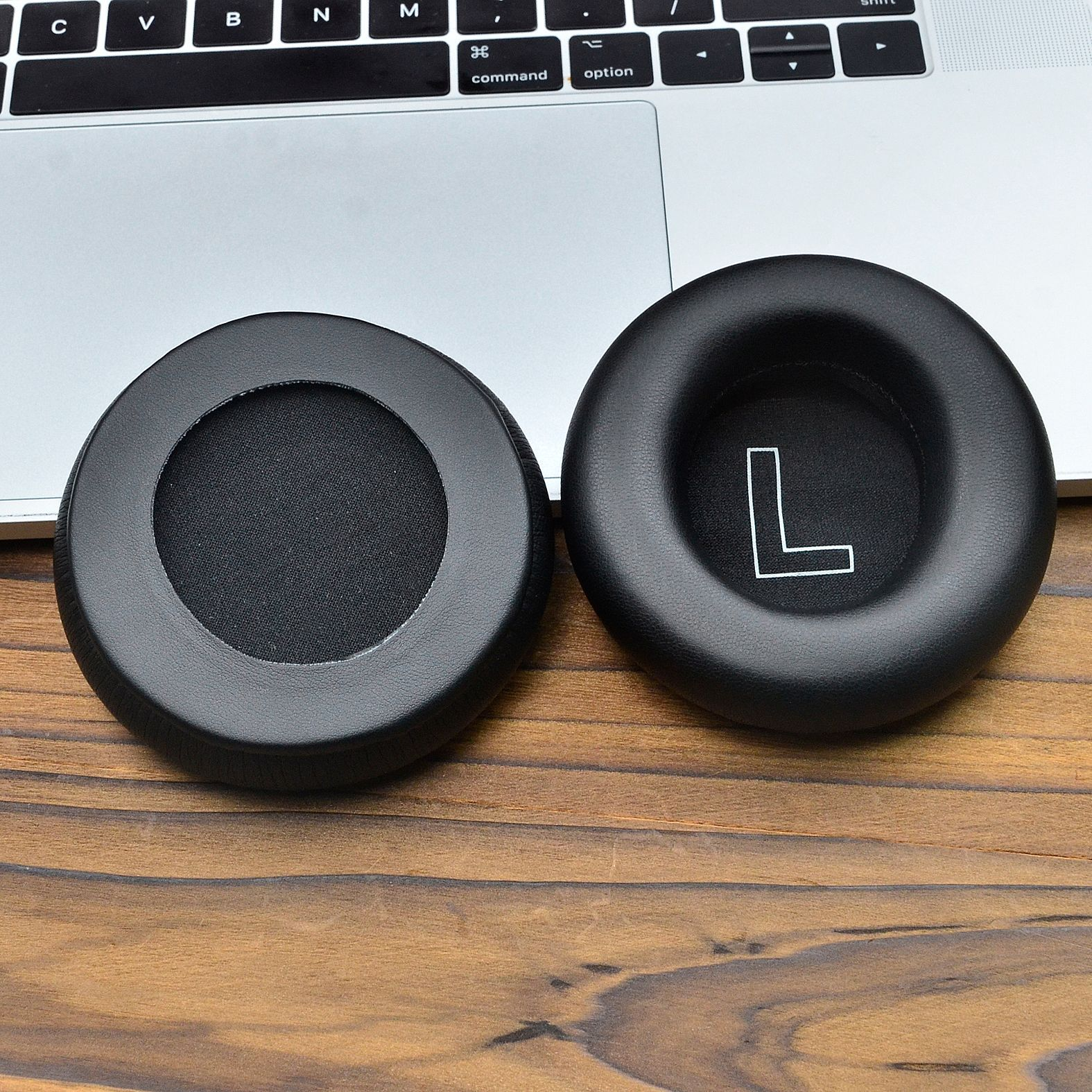 Nauszniki do słuchawek, jeden z oznaczeniem „L”, na drewnianej powierzchni.