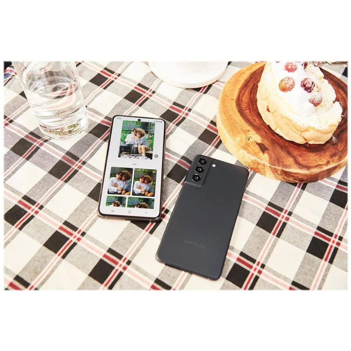 Smartfon ze zdjęciami na stole. Drugi telefon na stole. Ciasto na drewnianej desce, szklanka wody.