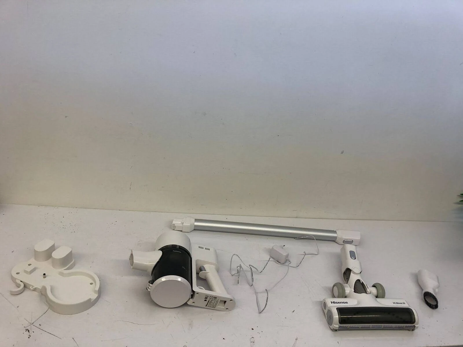 Piezas de aspiradora, incluyendo motor, tubo de extensión y cepillo, sobre una superficie blanca.