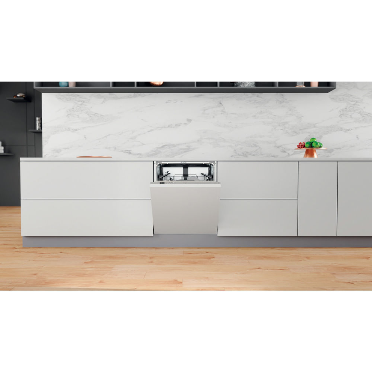 Lavastoviglie con porta aperta. Armadi bianchi con pavimento in legno. Alzatina in marmo, decorazioni verdi e rosse.