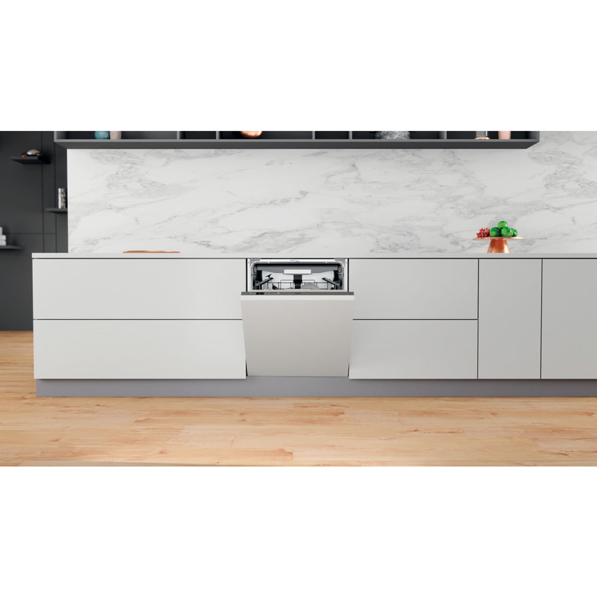 Cucina bianca con lavastoviglie. Porta della lavastoviglie aperta. Pavimento in legno. Mobili bianchi e alzatina in marmo.