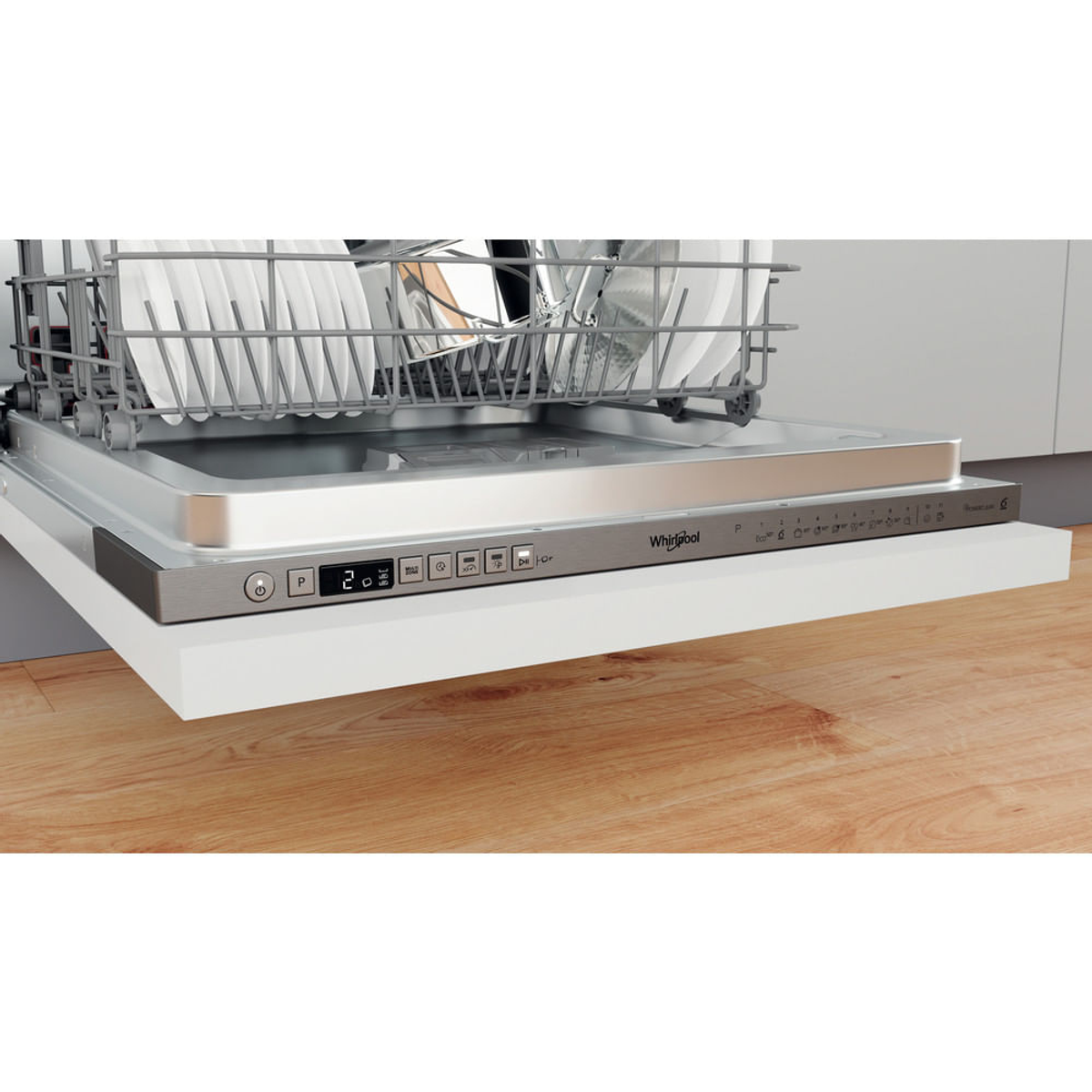 Lavastoviglie, aperta, con piatti nel cestello superiore. Pannello di controllo Whirlpool, superficie bianca, legno sotto.