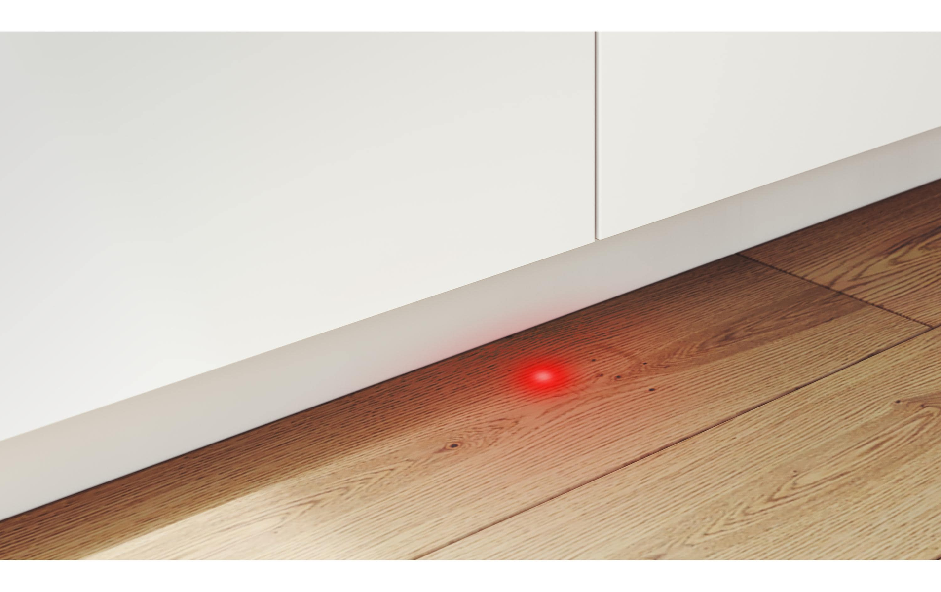 Ein rotes Licht auf dem Boden, in der Nähe eines weißen Schranks.