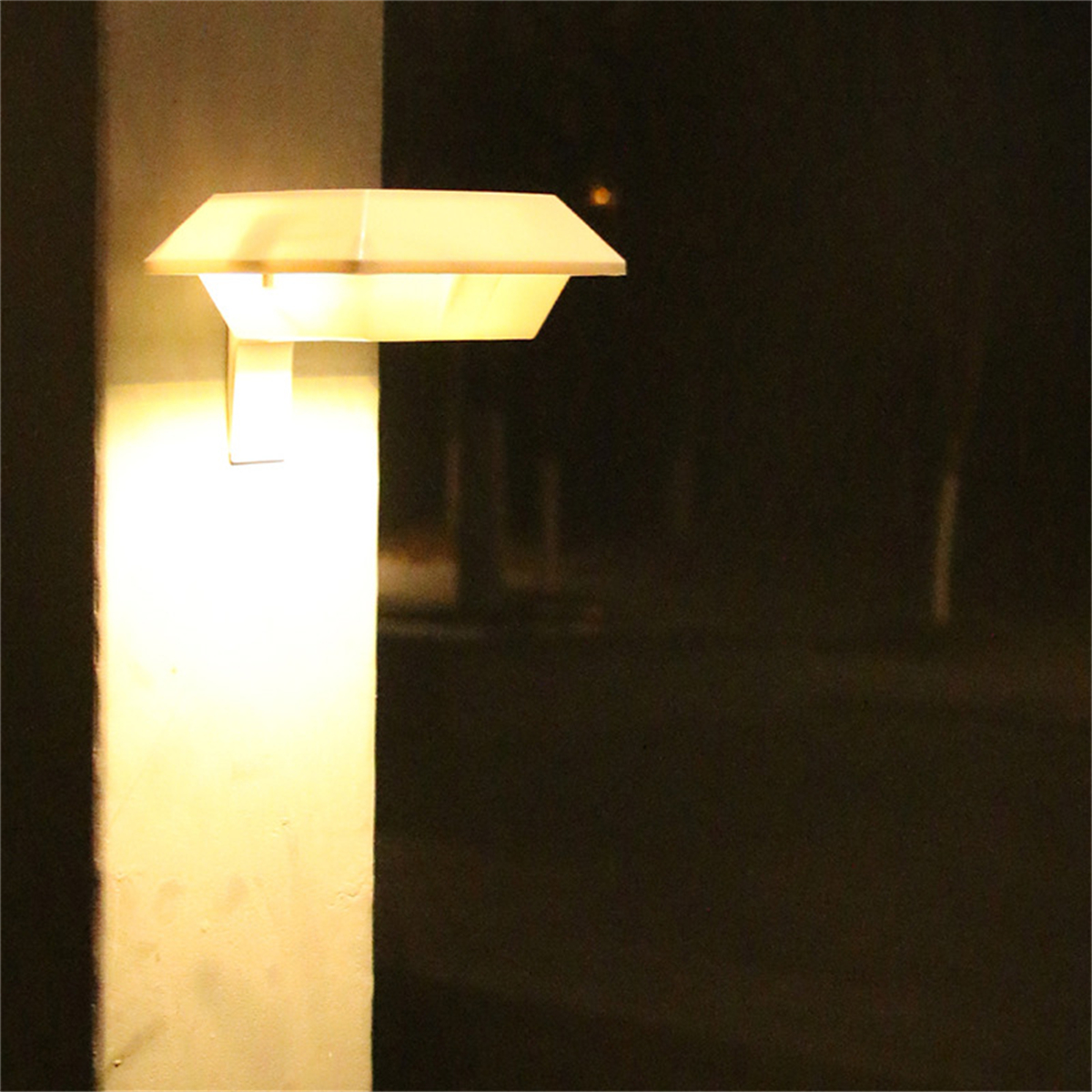 Eine Wandlampe mit weißem Oberteil und einem Lichtstrahl, der auf eine weiße Wand scheint.