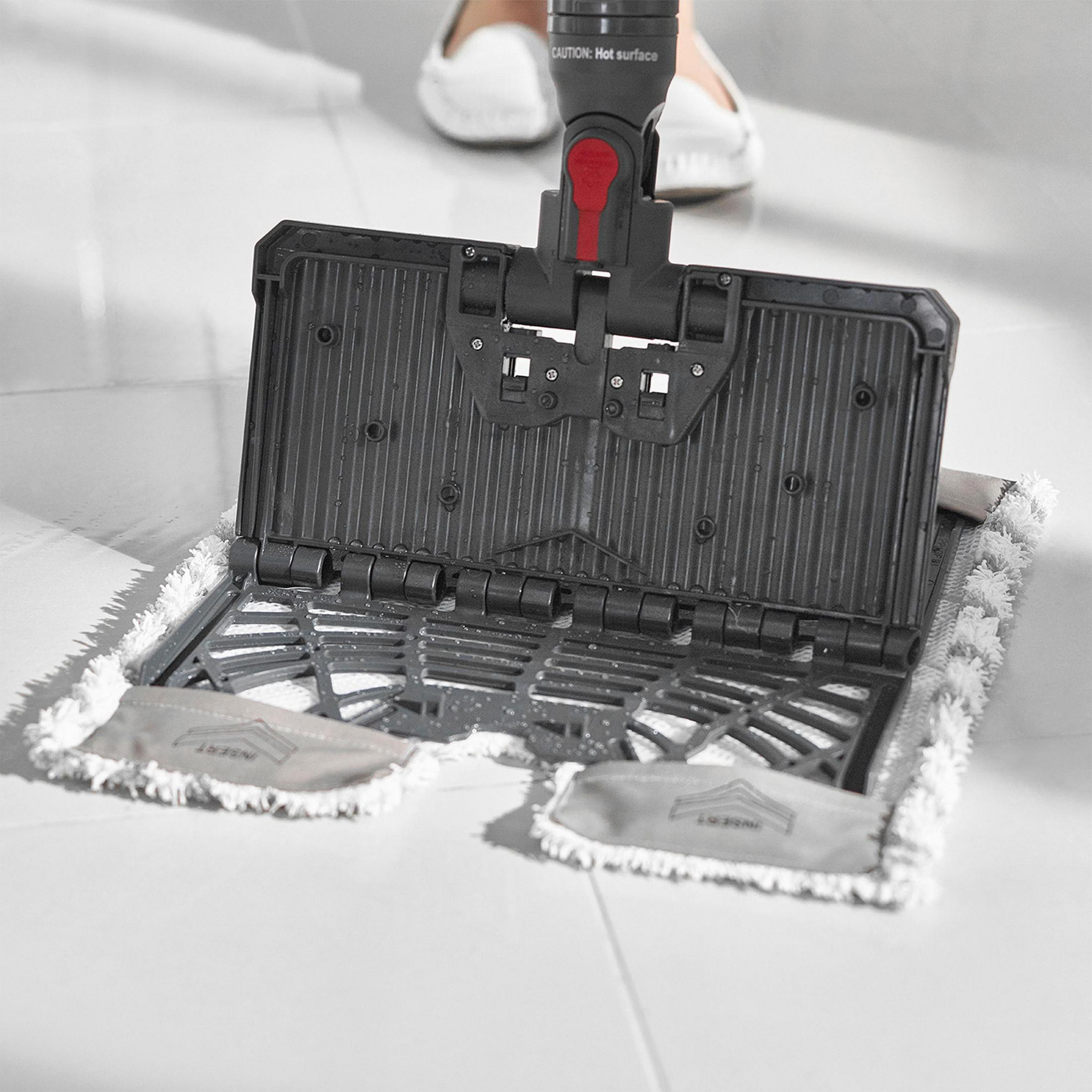 Głowica mopa ze stopą w tle. Mop jest otwarty, na podłodze wyłożonej płytkami.