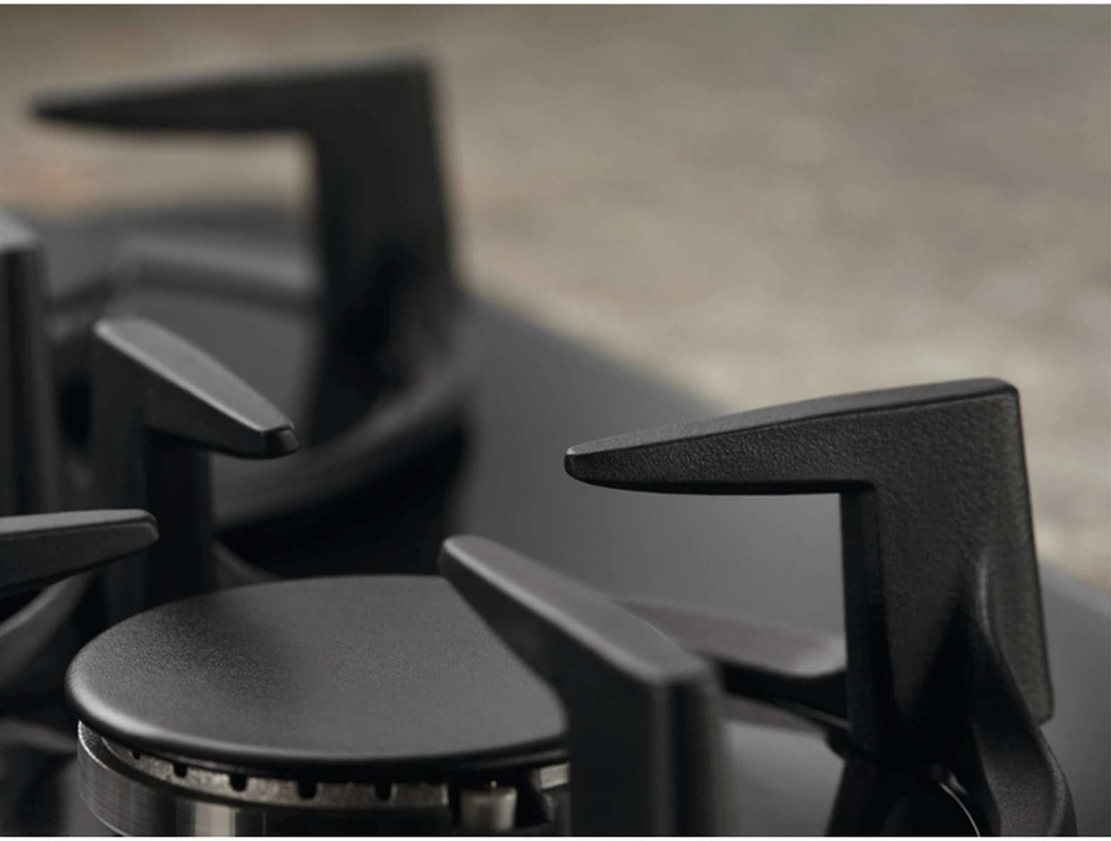 Zbliżenie czarnych rusztów palnika kuchenki gazowej.