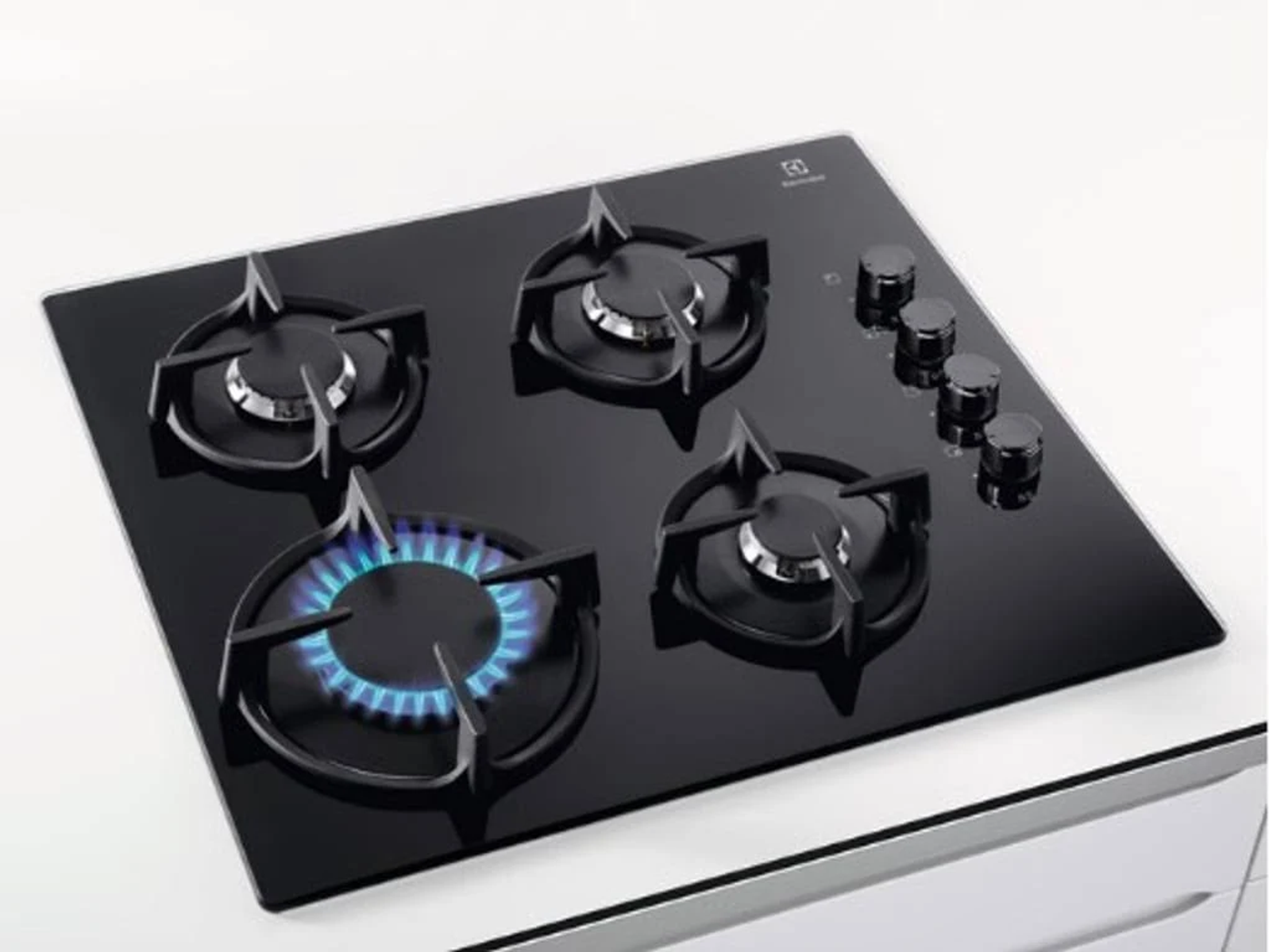 Czarna kuchenka z czterema palnikami, trzema pokrętłami i niebieskim płomieniem.