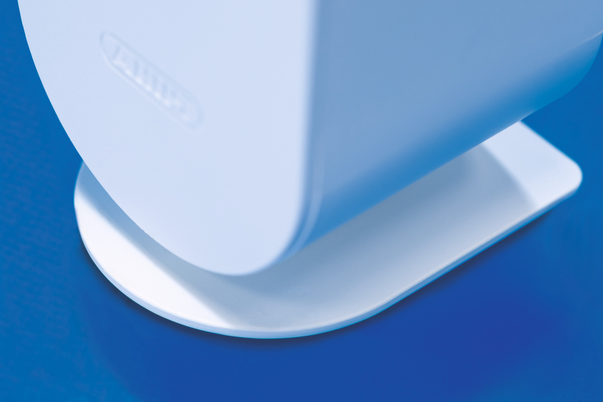 Weißes Kunststoffteil in gebogener Form. Blauer Hintergrund. Artikel hat ein Logo.