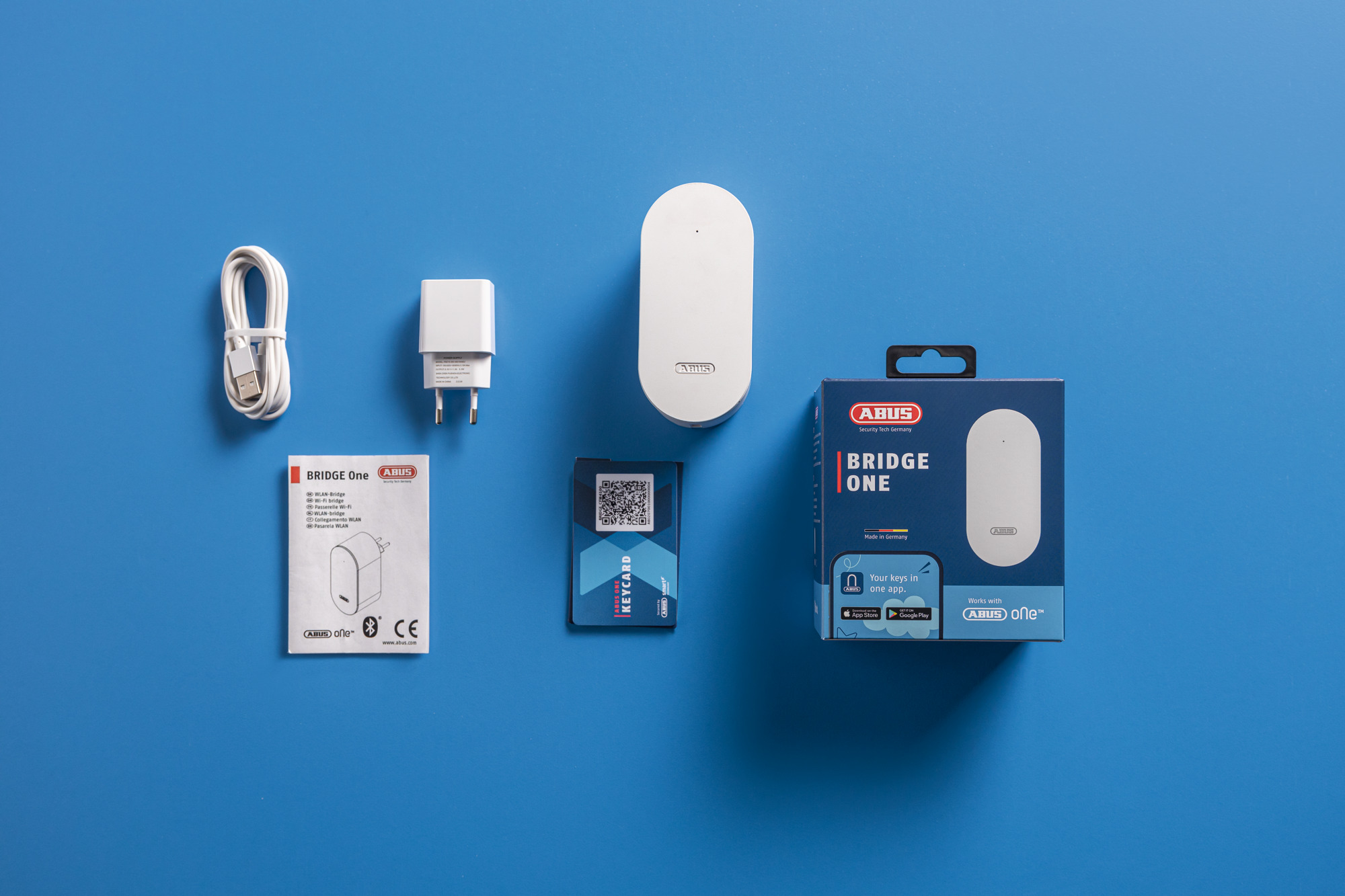 Ein Set von Heim-Sicherheitsartikeln: ein weißes Gerät, ein Ladegerät, Kabel und eine Box.
