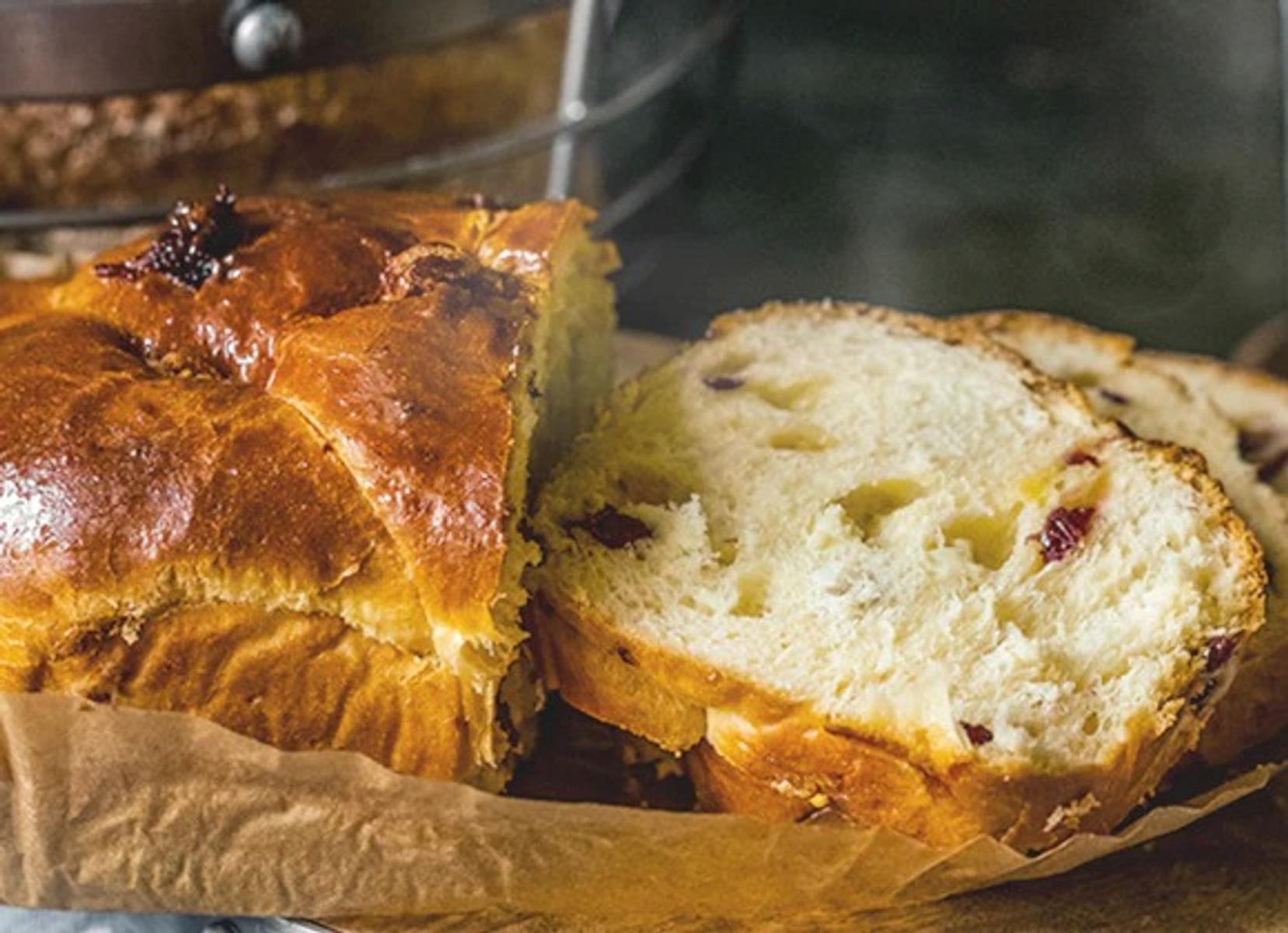 Fetta di pane con uvetta e crosta dorata su carta marrone.