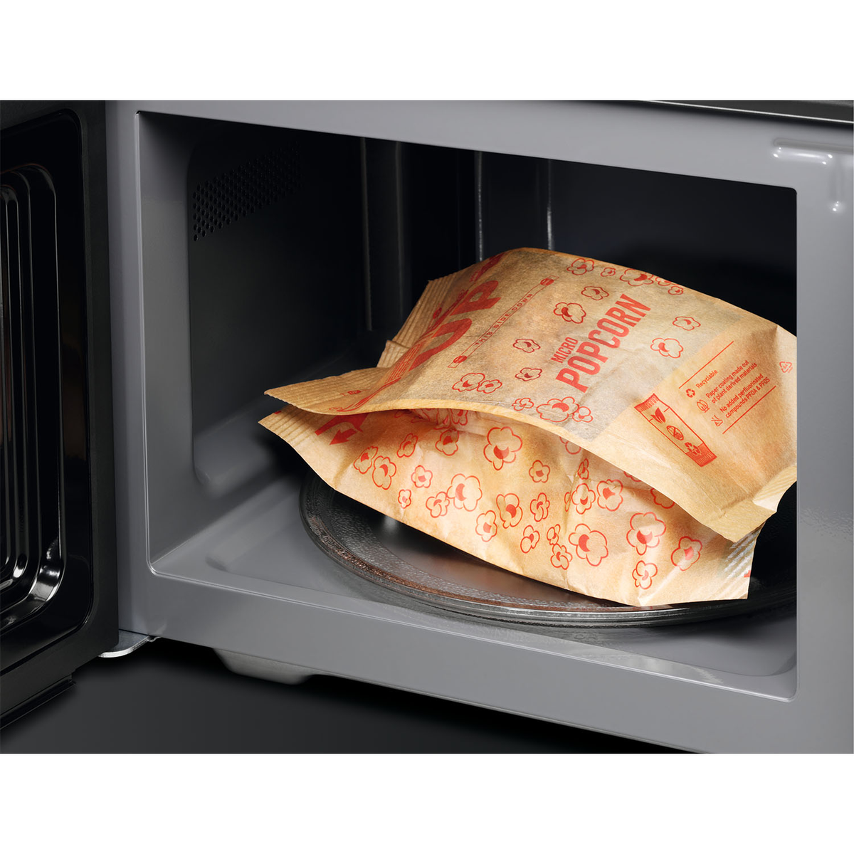 Magnetroninterieur met twee zakken popcorn op een roterende glazen plaat.