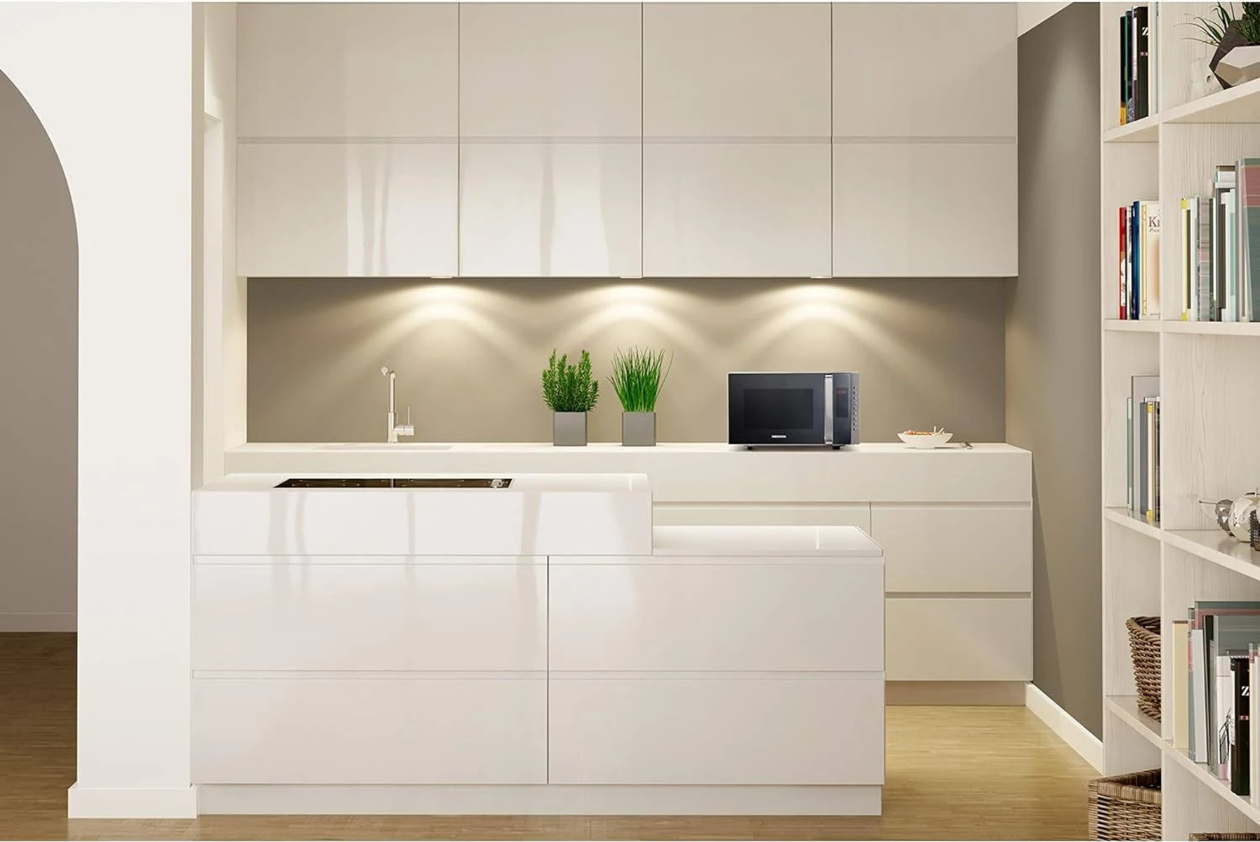 Cucina moderna con mobili bianchi, microonde, piante e libreria.