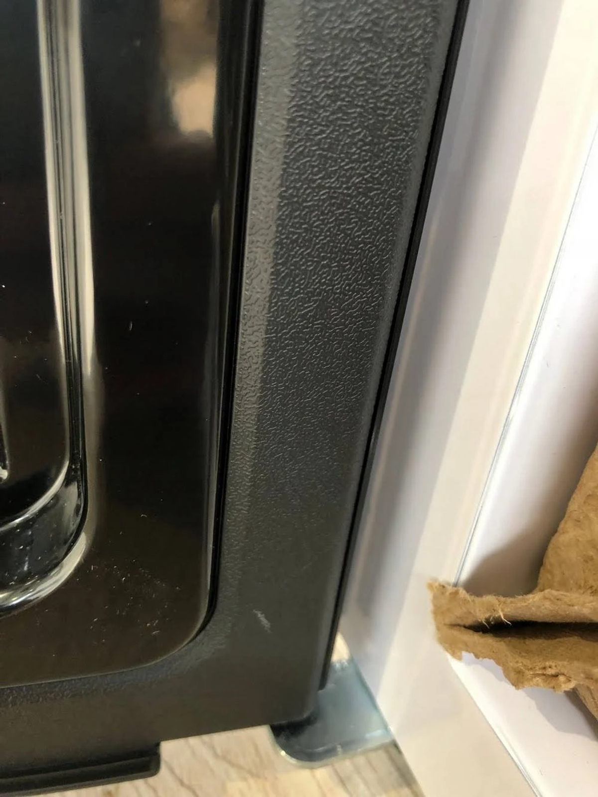Primer plano de un electrodoméstico negro con un lado de plástico texturizado y un lado blanco.
