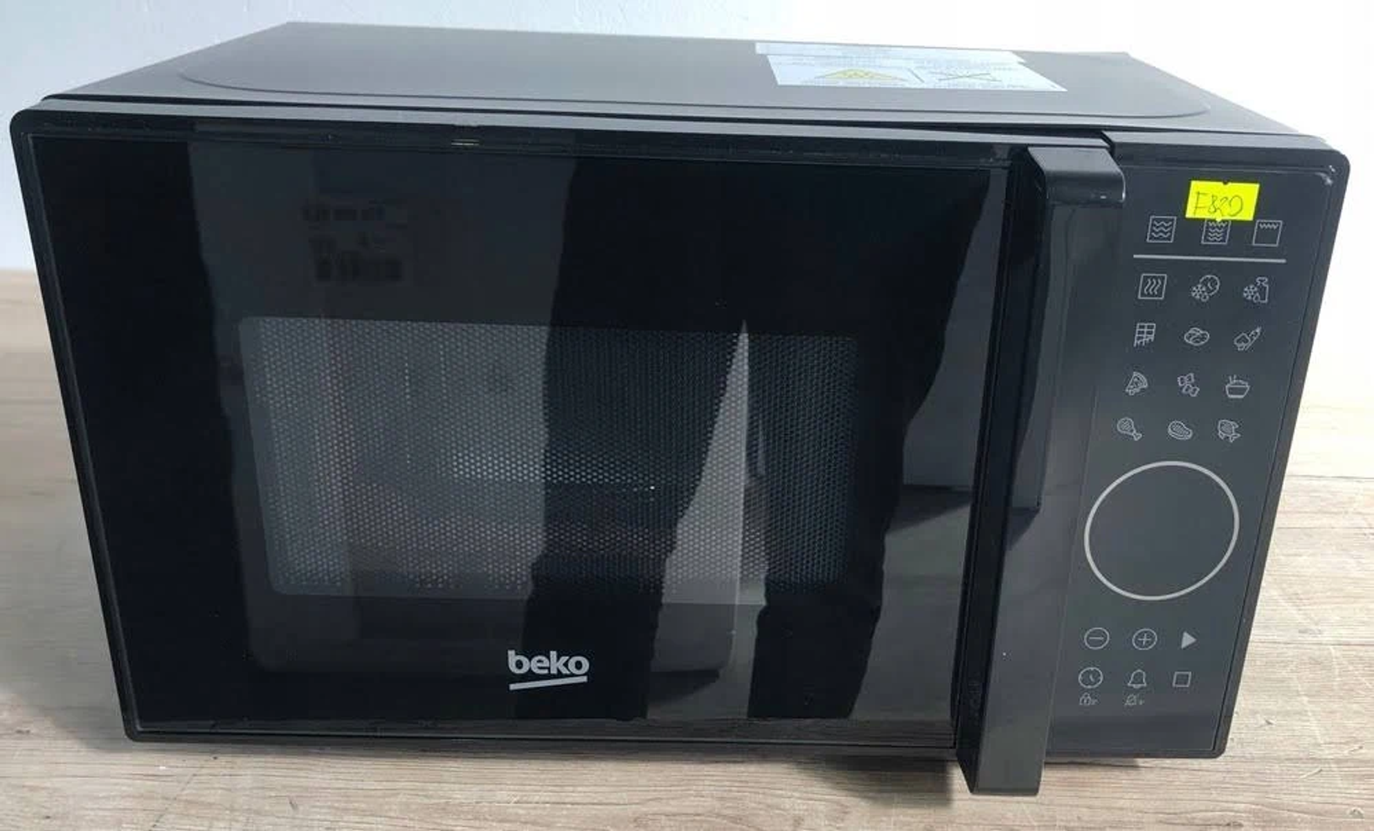 Horno microondas negro con pantalla digital y panel de control. La marca es Beko.