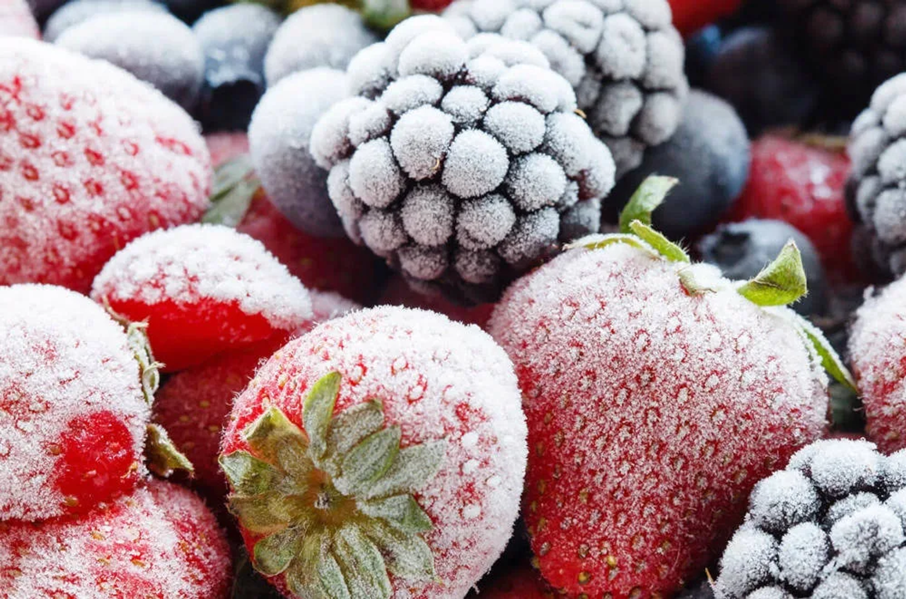 Primer plano de bayas congeladas: fresas, arándanos y moras, cubiertas de escarcha.