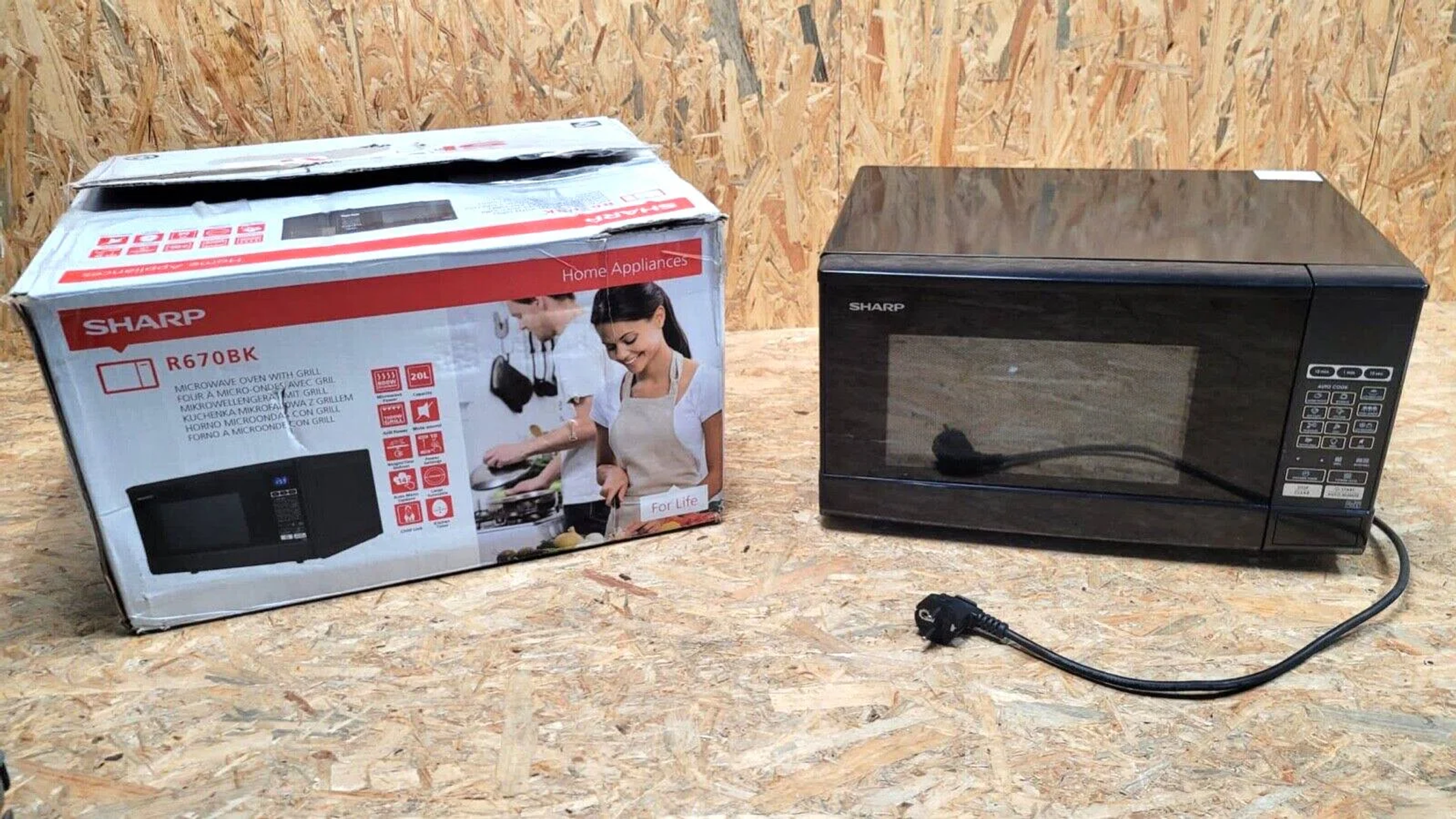 Horno microondas en una caja y el horno en sí. Marca Sharp. Sobre una superficie de madera.