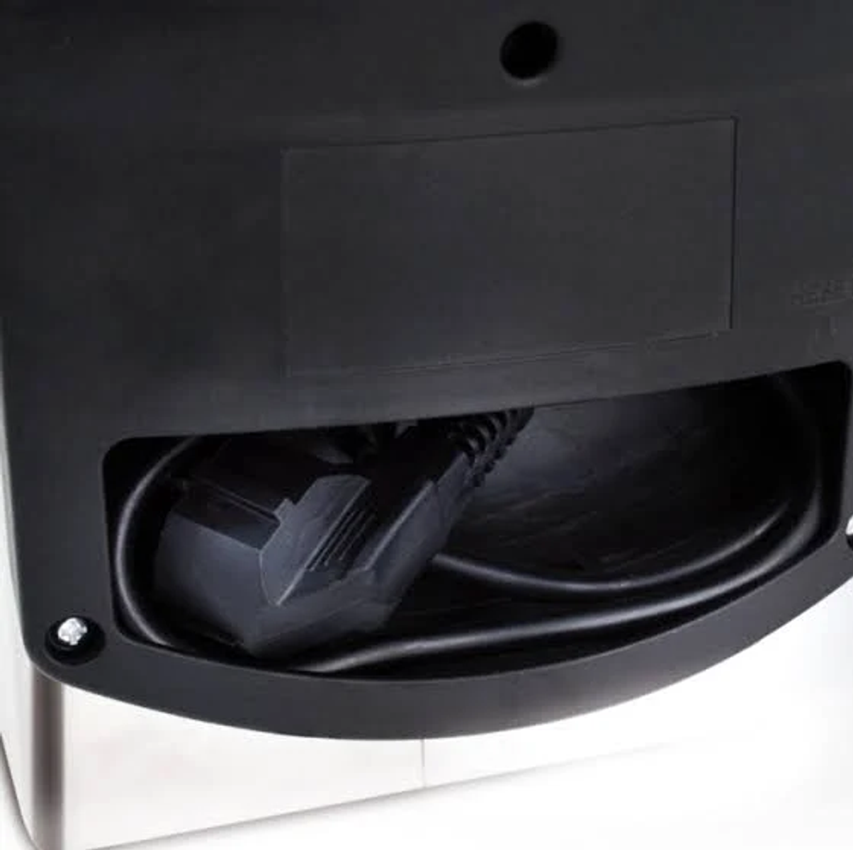 Primer plano de la parte trasera de un horno microondas, mostrando el cable de alimentación y la conexión.