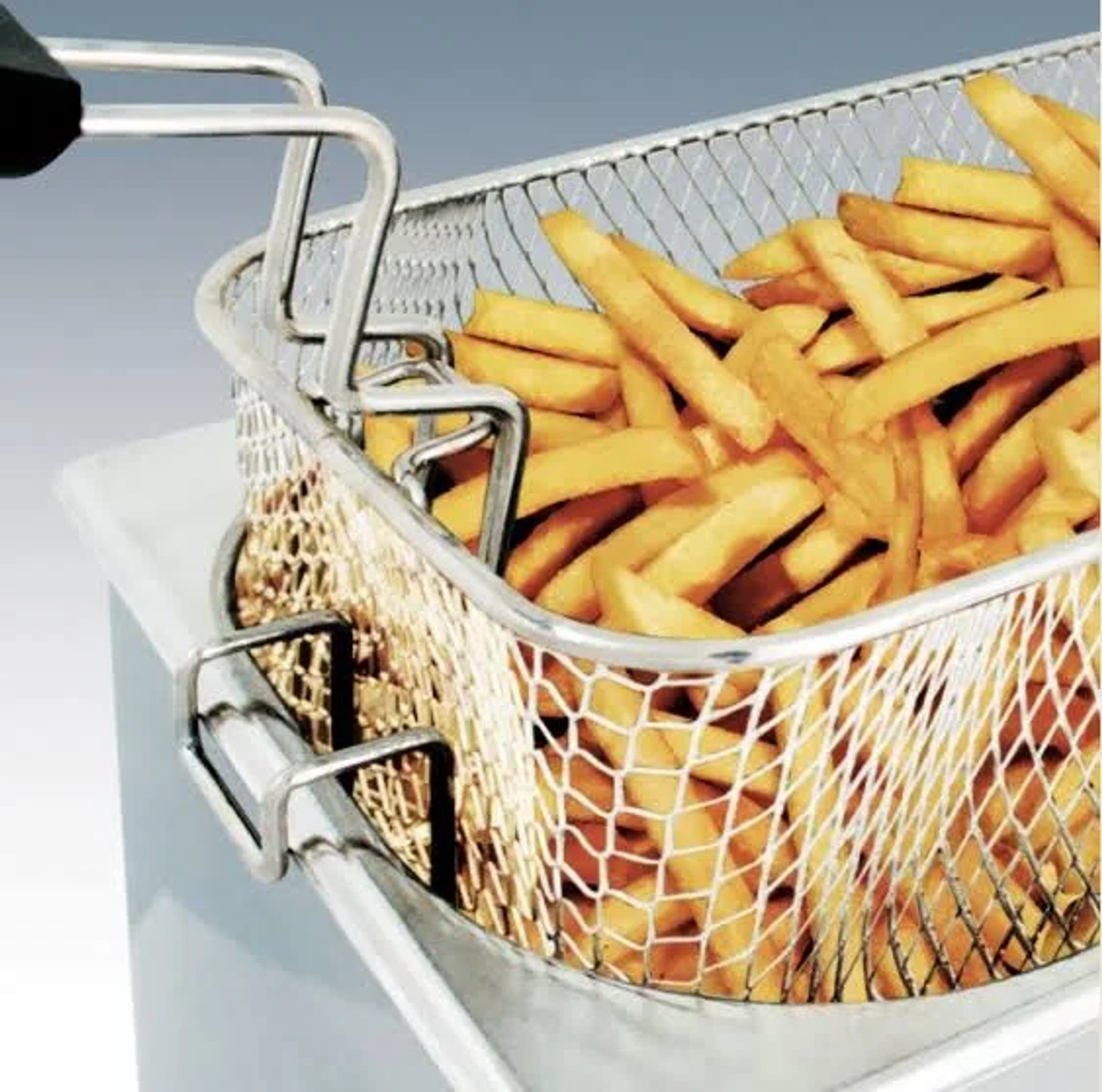 Una cesta metálica llena de patatas fritas doradas, listas para servir después de freír.