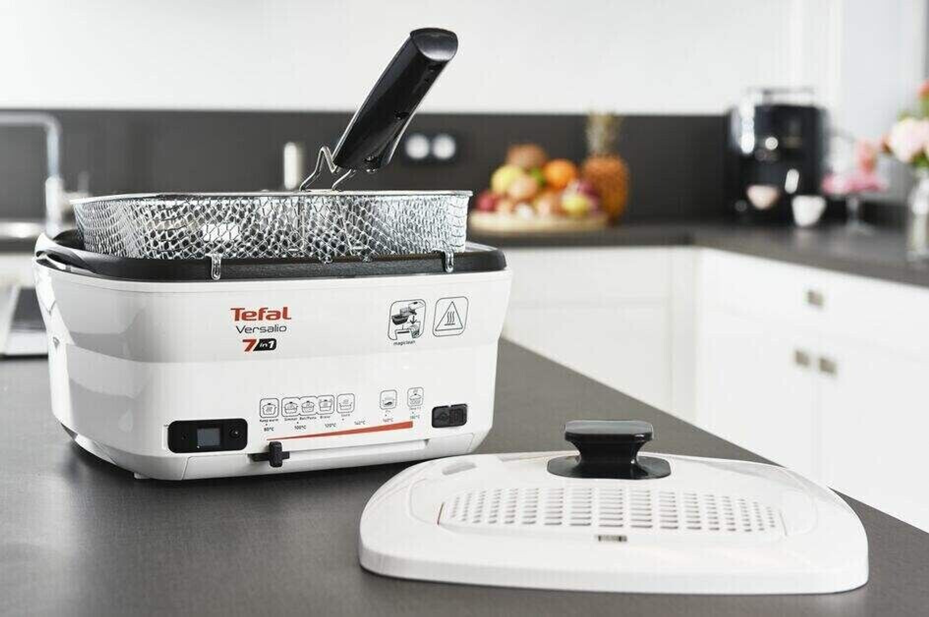 Biała i szara frytkownica z akcesoriami. Pokrywa otwarta, pokazująca kosz w środku.
