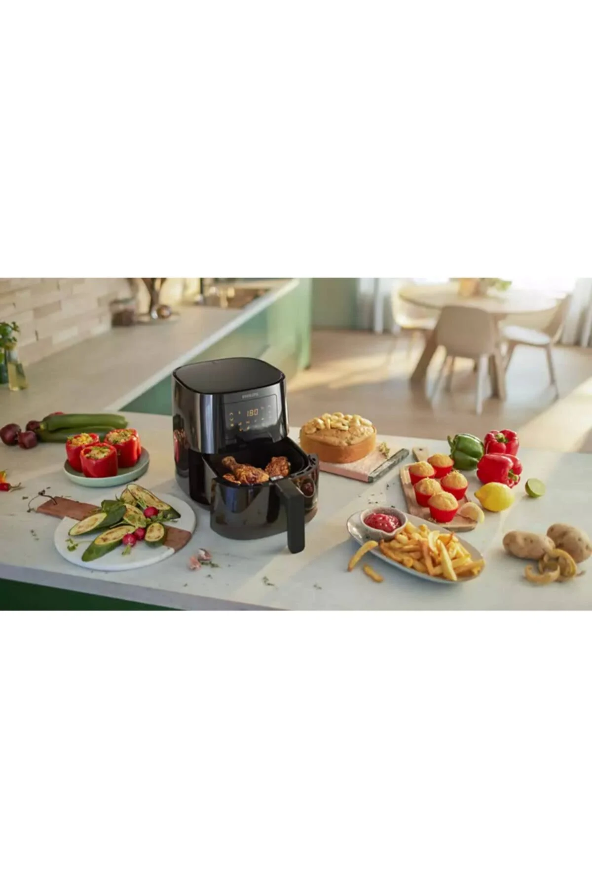 Una friggitrice ad aria con cibo intorno. Include cibi fritti, peperoni, patate e una torta. Ambiente cucina.