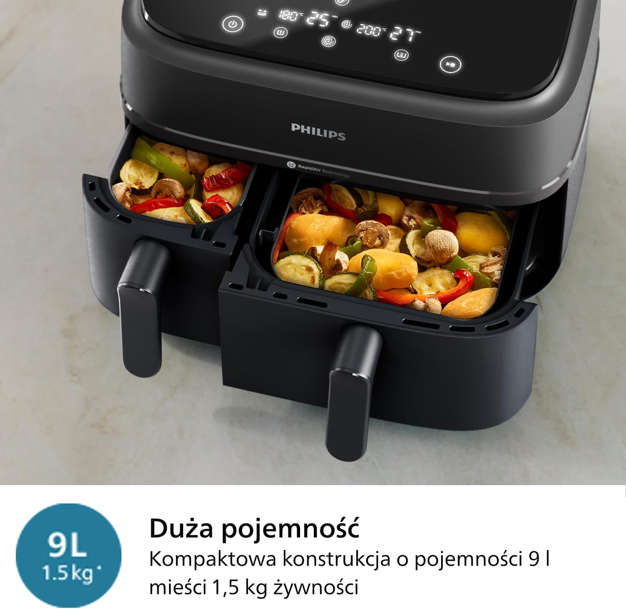 Freidora de aire negra con dos bandejas de verduras cocidas, logotipo de Philips arriba.