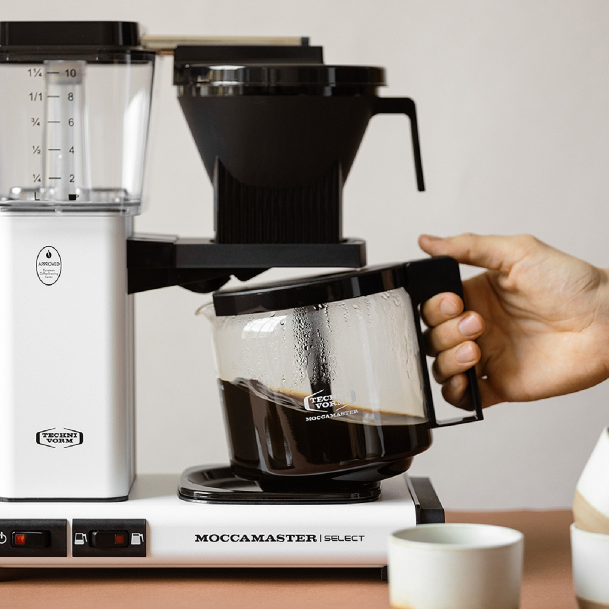 Moccamaster koffiezetapparaat met glazen kan en koffie wordt geschonken.